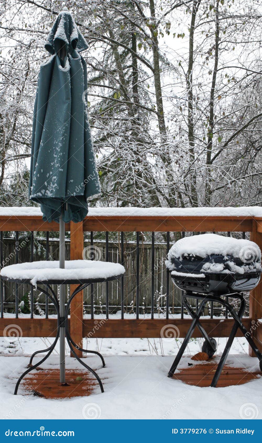 Snow Covered Deck. Snow covering a wood deck with a table, Umbrella and BBQ grill