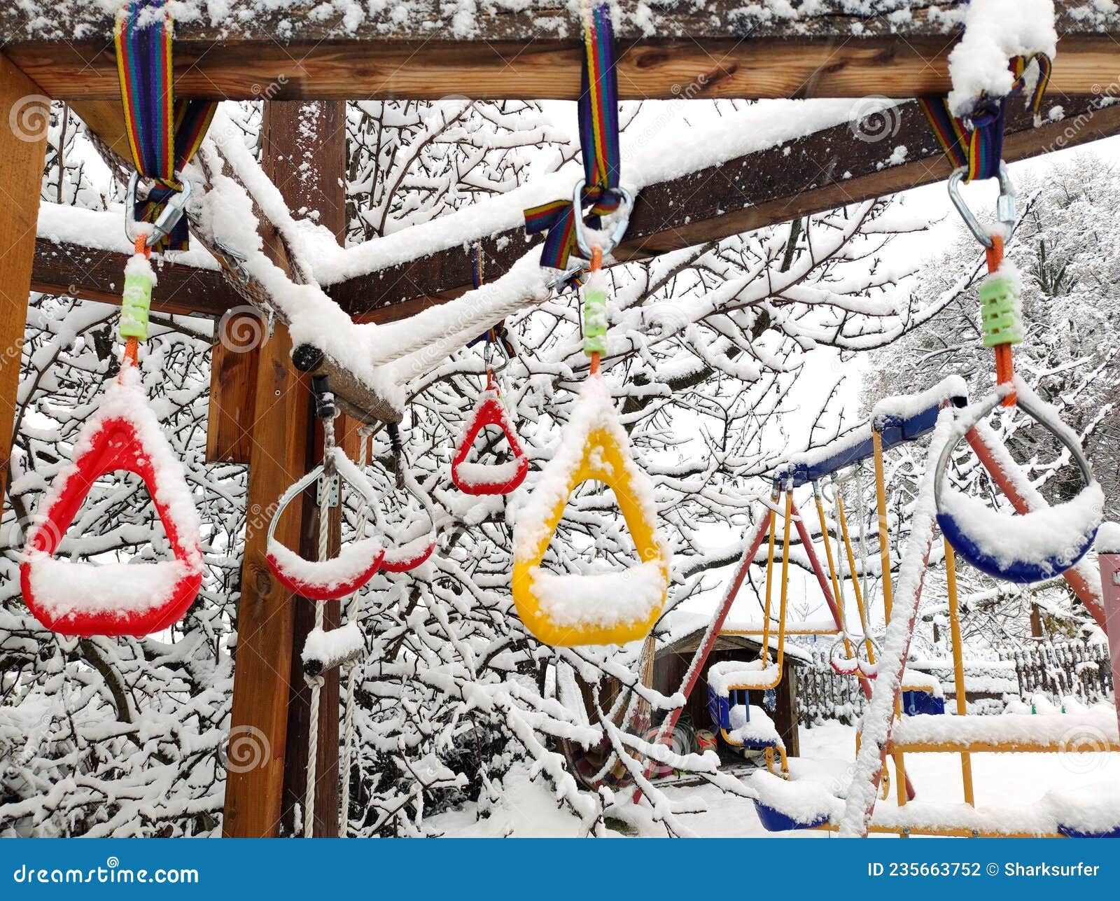 snow-covered handholds on monkey bars at kids playground