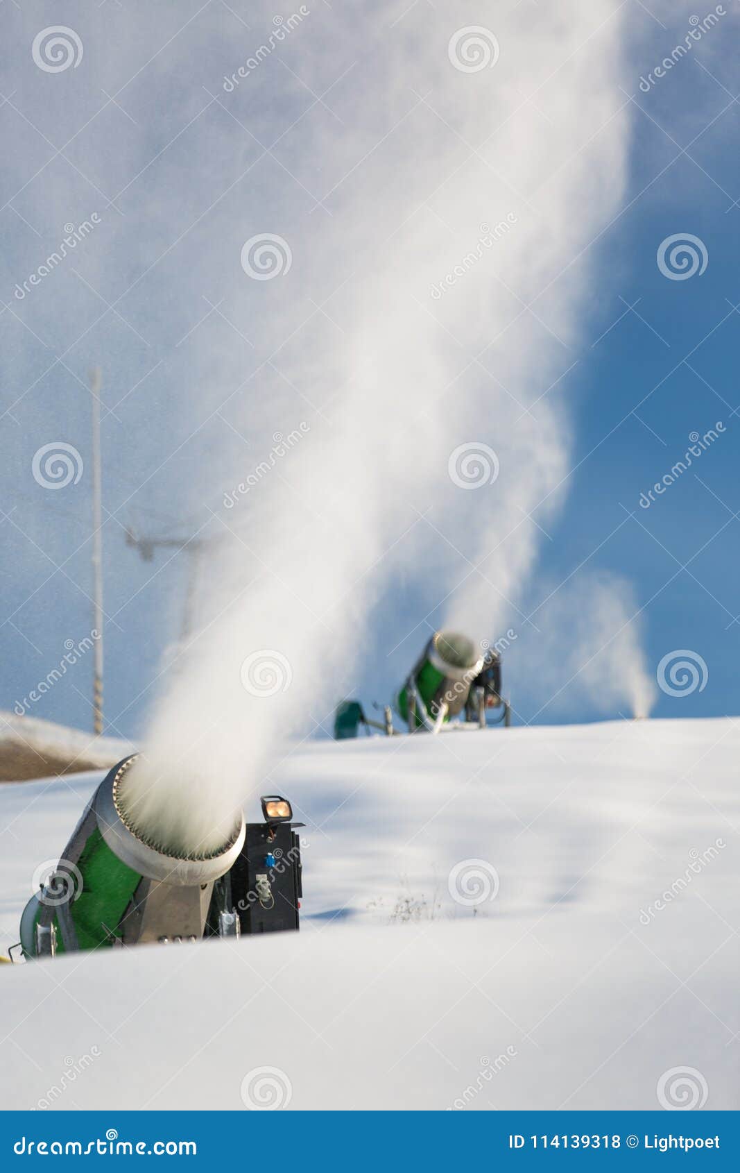 snow-machine bursting artificial snow over a skiing slope