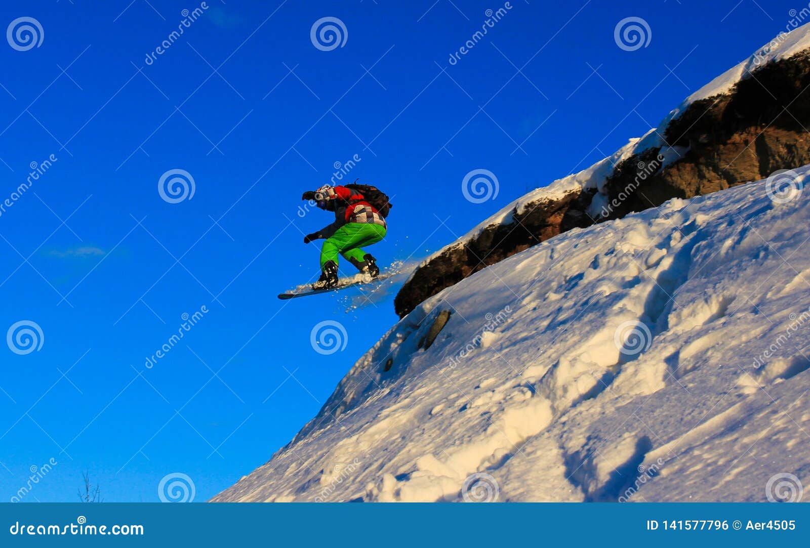 Snowboard jump off a cliff stock photo. Image of slide 141577796