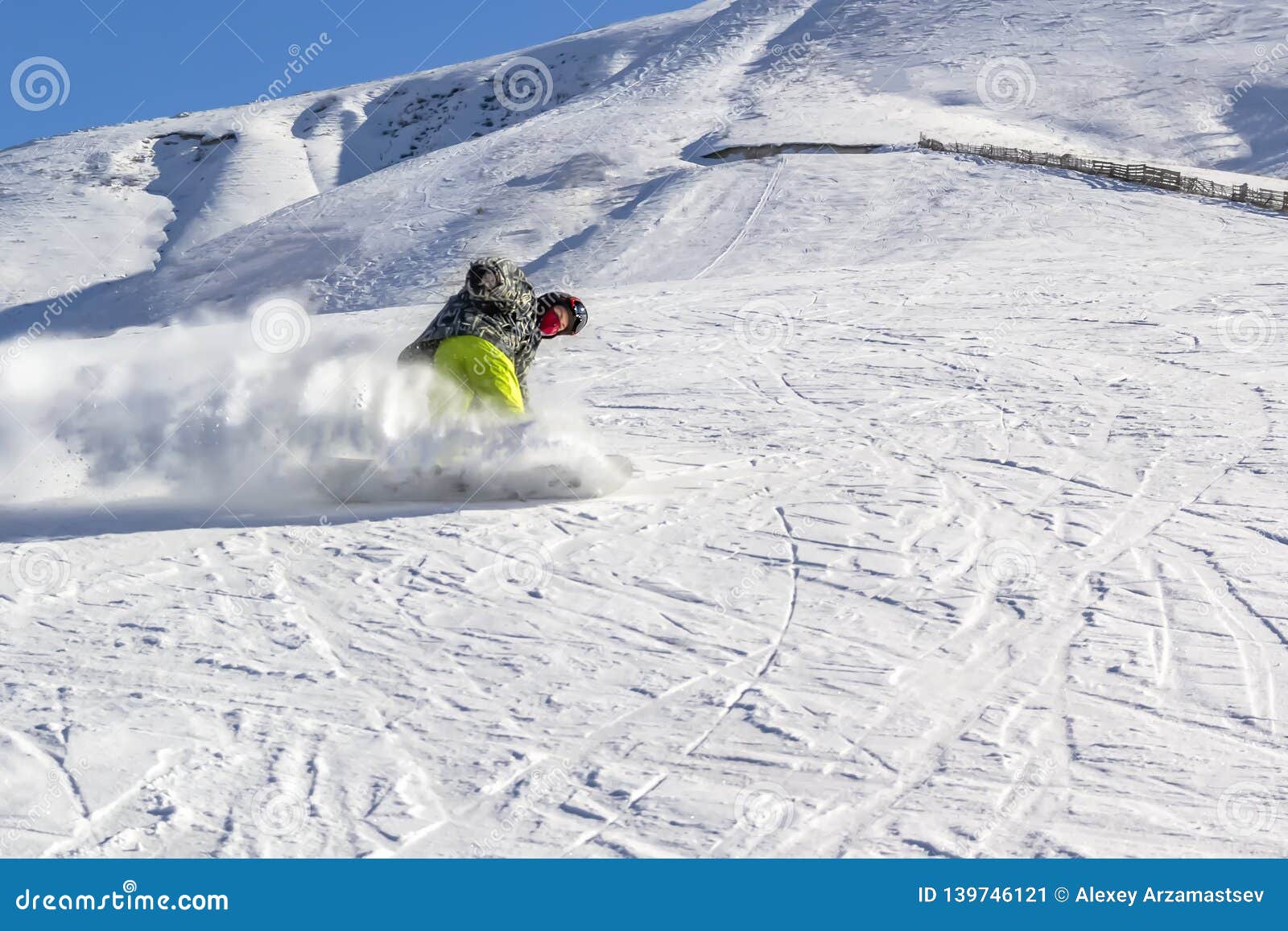 Snowboarder Quickly Rolls Downhill in a Cloud of Snow Dust Against a ...