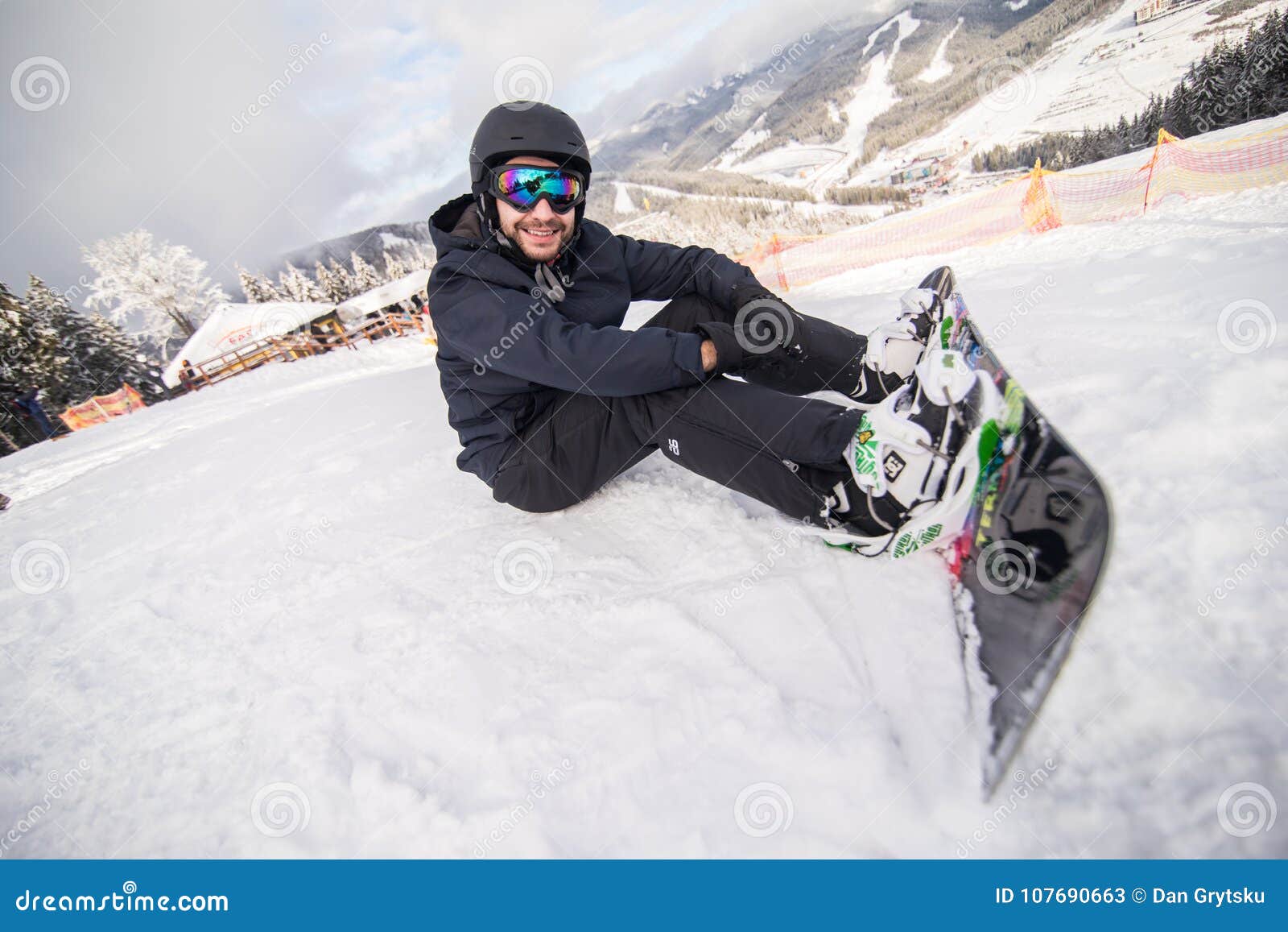 Snowboarder Sitting on a Ski Slope before Ride Editorial Stock Photo
