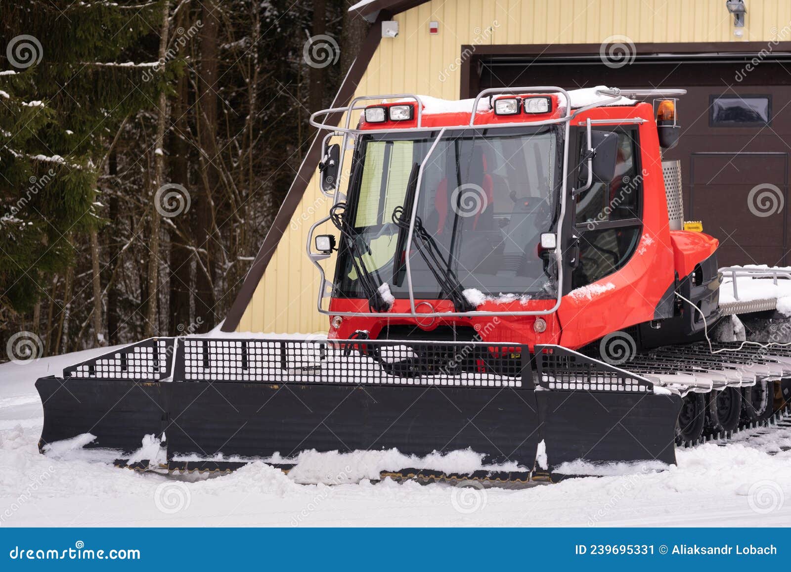 A Snowplow on Red Tracks Standing in Winter in the Forest Near the Barn