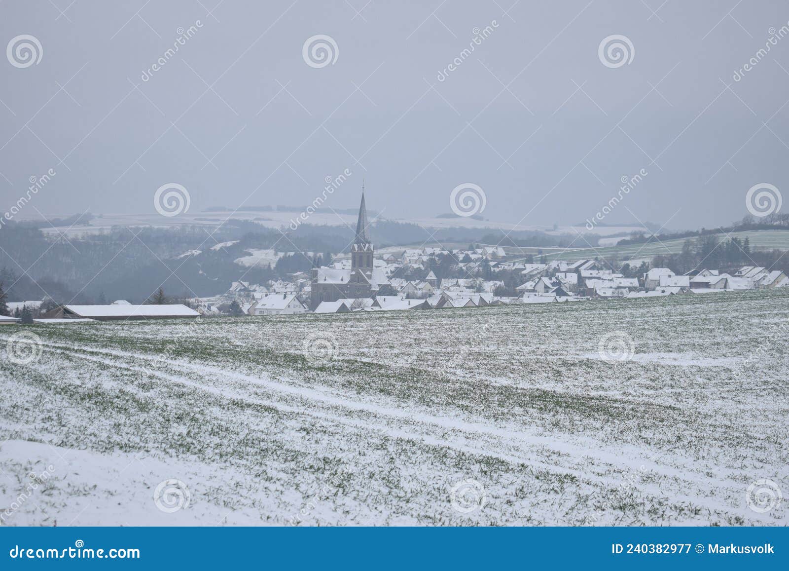 snowy landscape in the eifel with the village welling in a valley