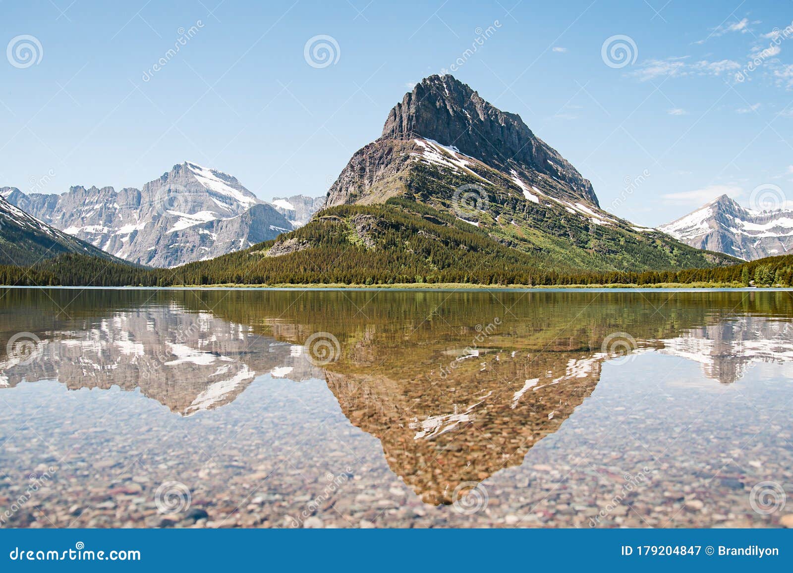 a snowy mountain water reflection on swiftcurrent lake in many glacier region of glacier national park, montana. grinnell point, a