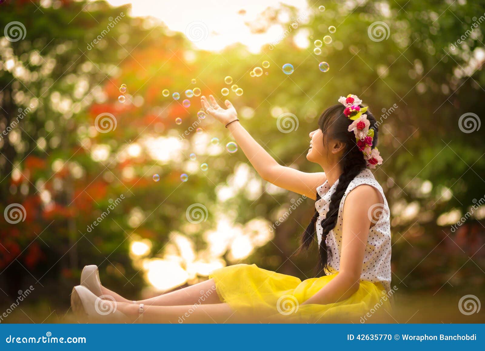 Asian teenager girl in the park under soap bubble rain