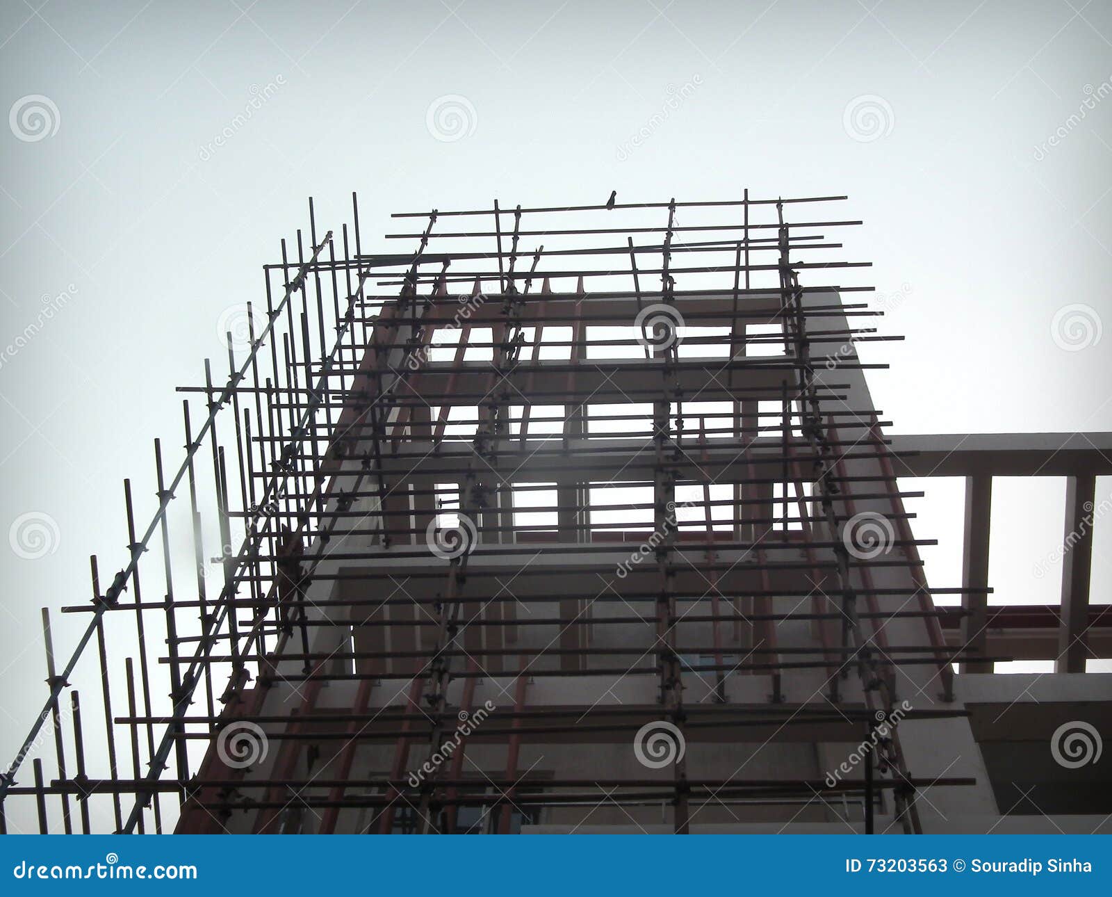 Uma construção alta da elevação sob a construção com a construção principal quase completa e cercada por uma estrutura de bambu