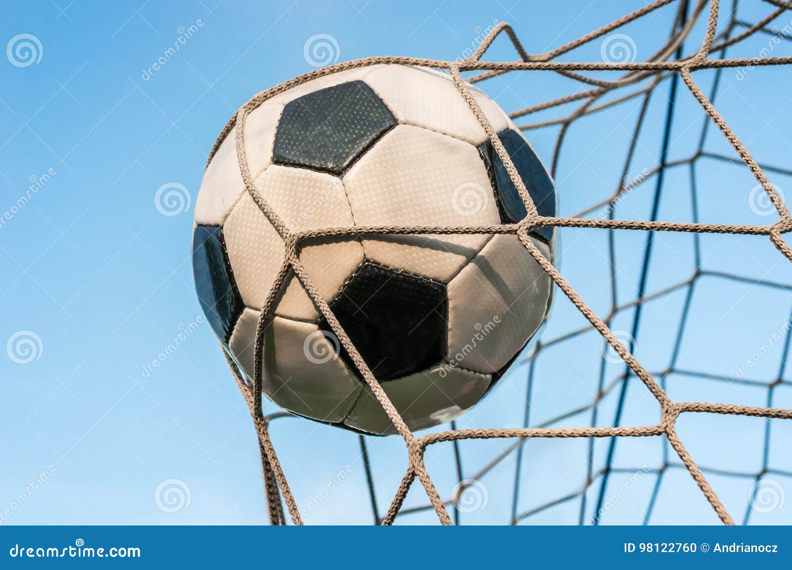 Soccer Ball in the Goal Net with Blue Sky Background Stock Photo