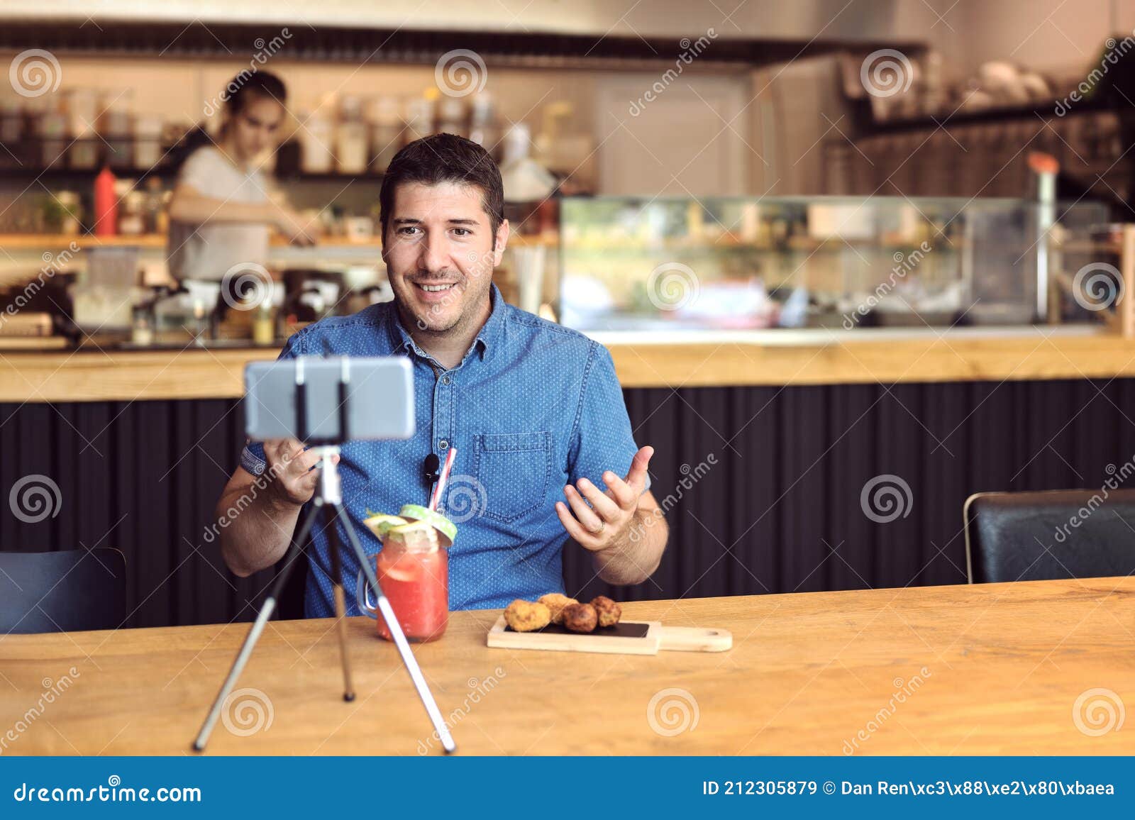 social media influencer or food blogger creating digital marketing content by filming video inside small business restaurant