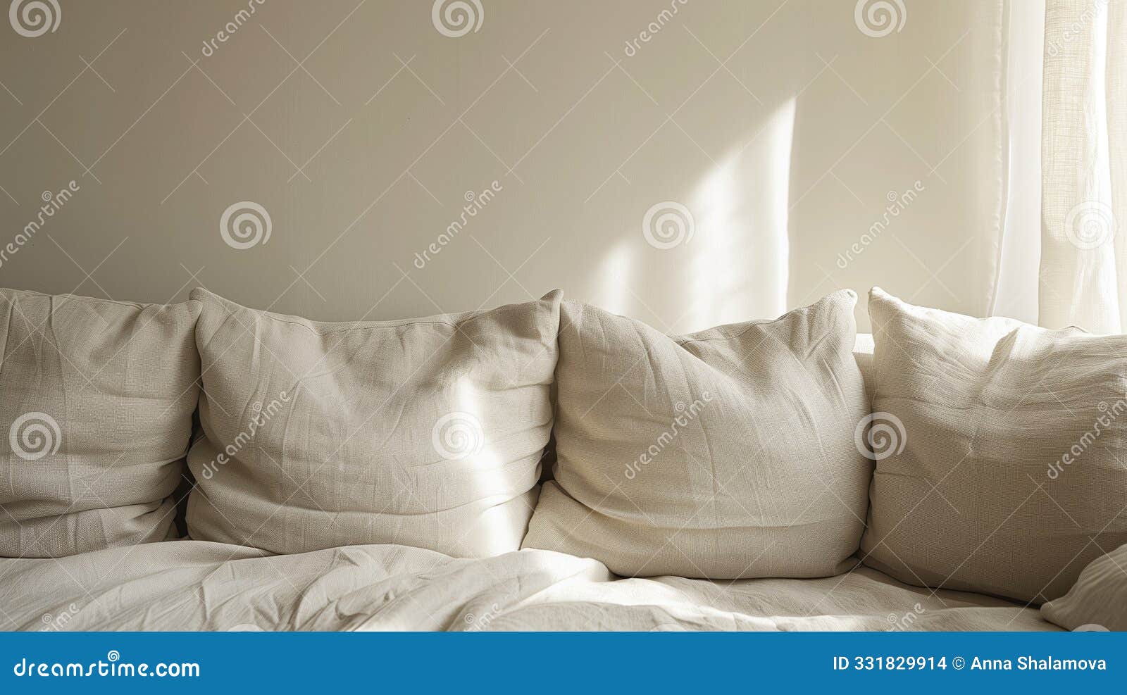 soft beige cushions lined up on a white couch against a minimalist wall.