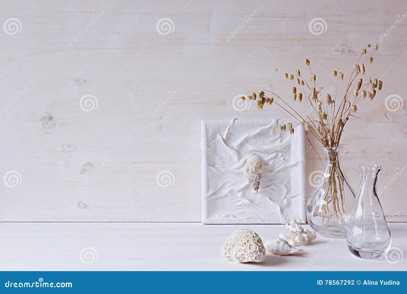 soft home decor. seashells and glass vase with spikelets on white wood background.
