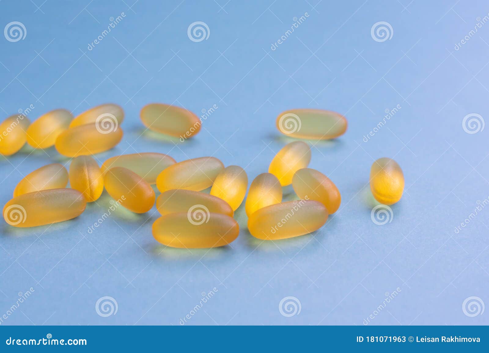 soft yellow jelly chewable pills filled by fish oil as a source of omega 3. capsules are lying on blue background