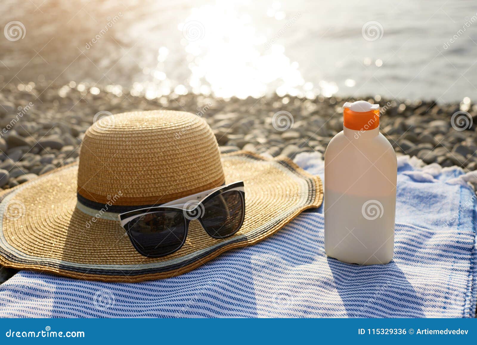 Solbrännakrämflaska och solglasögon på strandhandduken med havskusten på bakgrund Sunscreen på solstol utomhus på soluppgång eller solnedgång Hudomsorg och skyddsbegrepp