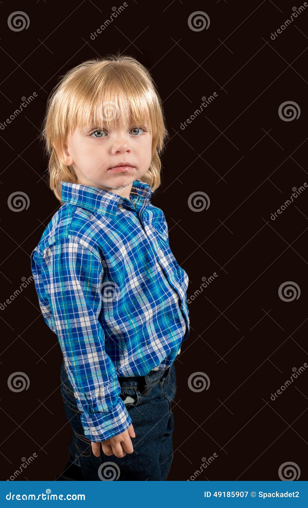 solemn little boy against a dark background