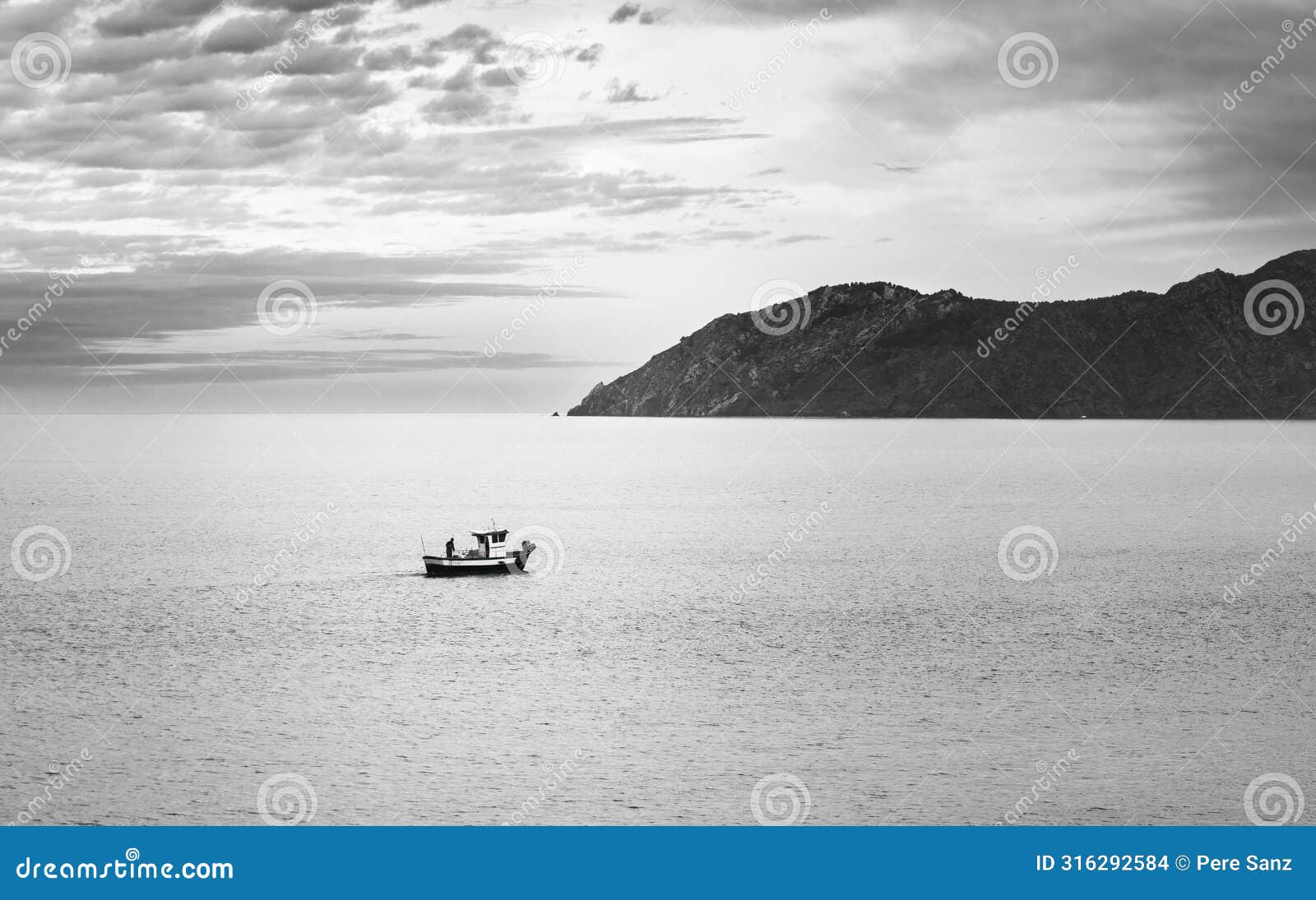solitary fishing boat at dusk near coastal mountain, catalonia