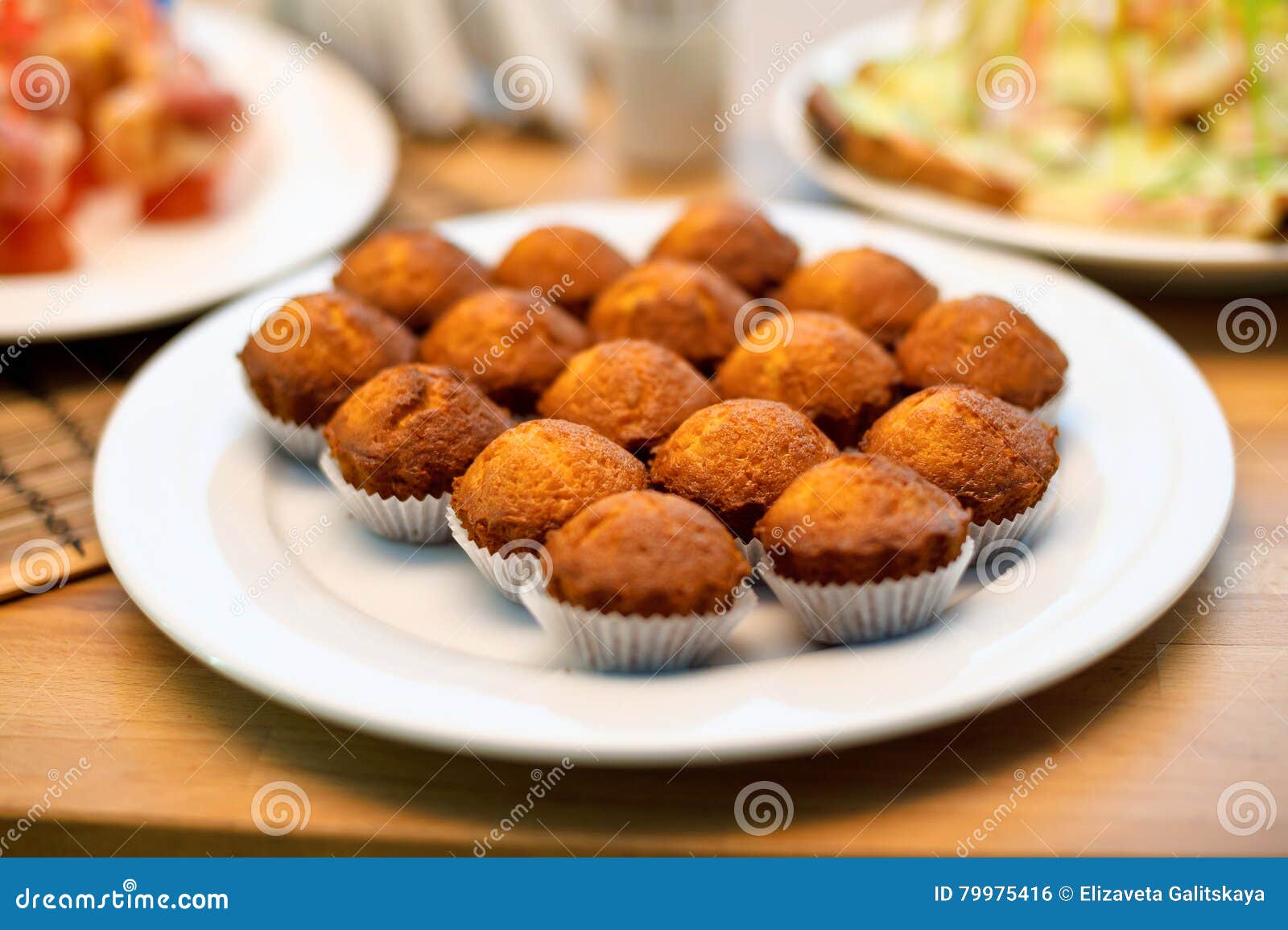 Some Appetizing Plain Muffins in a White Ceramic Plate on a Set Table