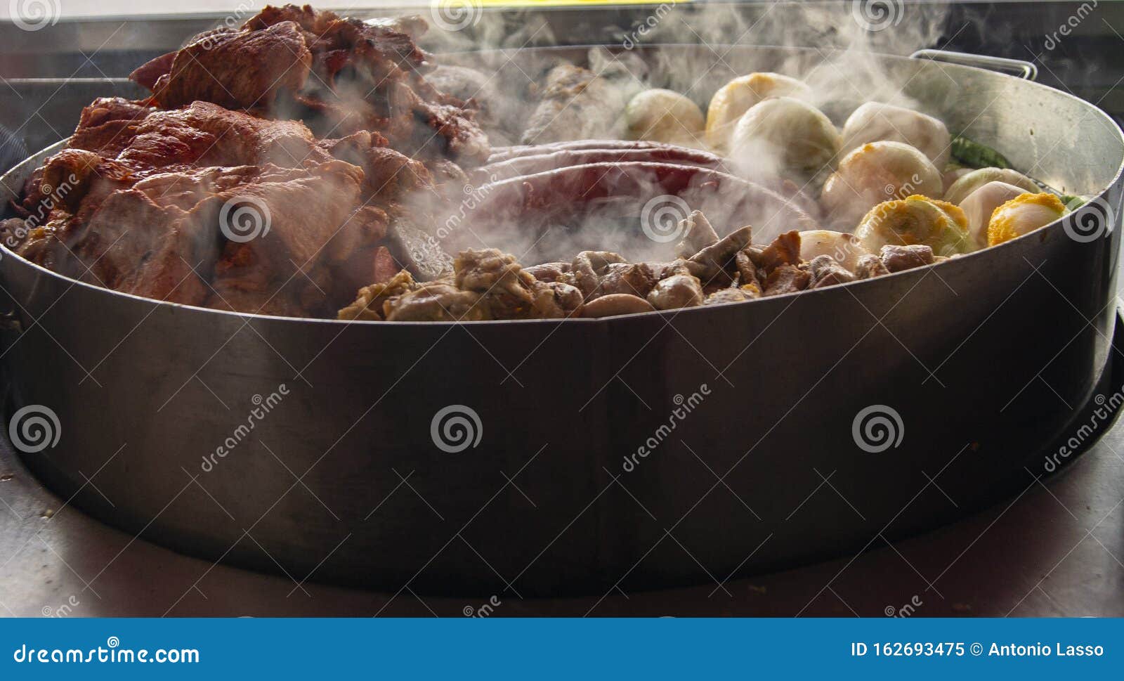 some types of meats and vegetables being coocked on a grill of a reustarant.