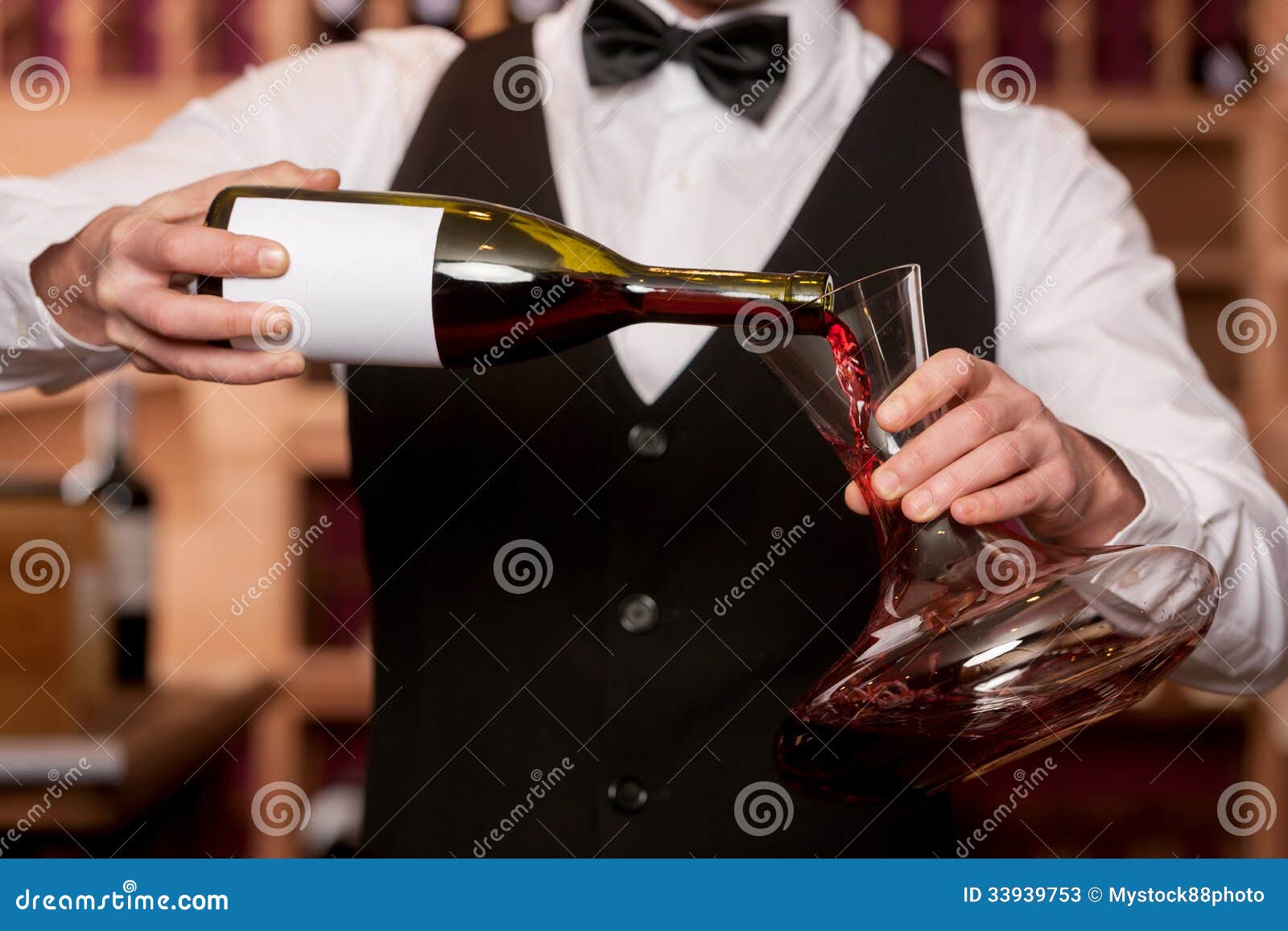 Sommelier with decanter. Cropped image of sommelier pouring wine to the decanter