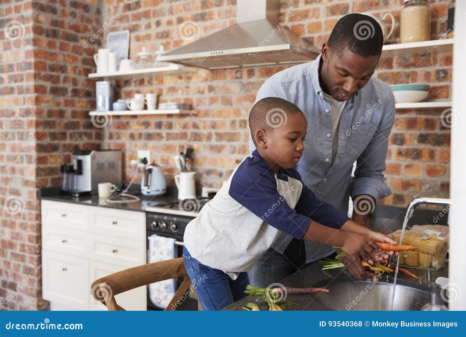 son helping father to prepare vegetables for meal in kitchen