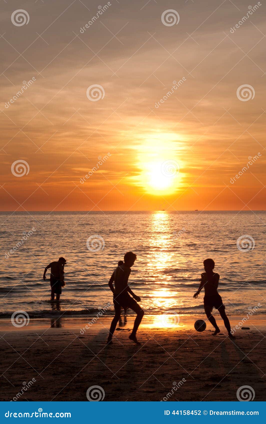 Sonnenuntergangstrand mit den Kindern, die Fußball spielen. Zwei Jugendliche spielen Fußball als schöner Sonnenuntergangstrand