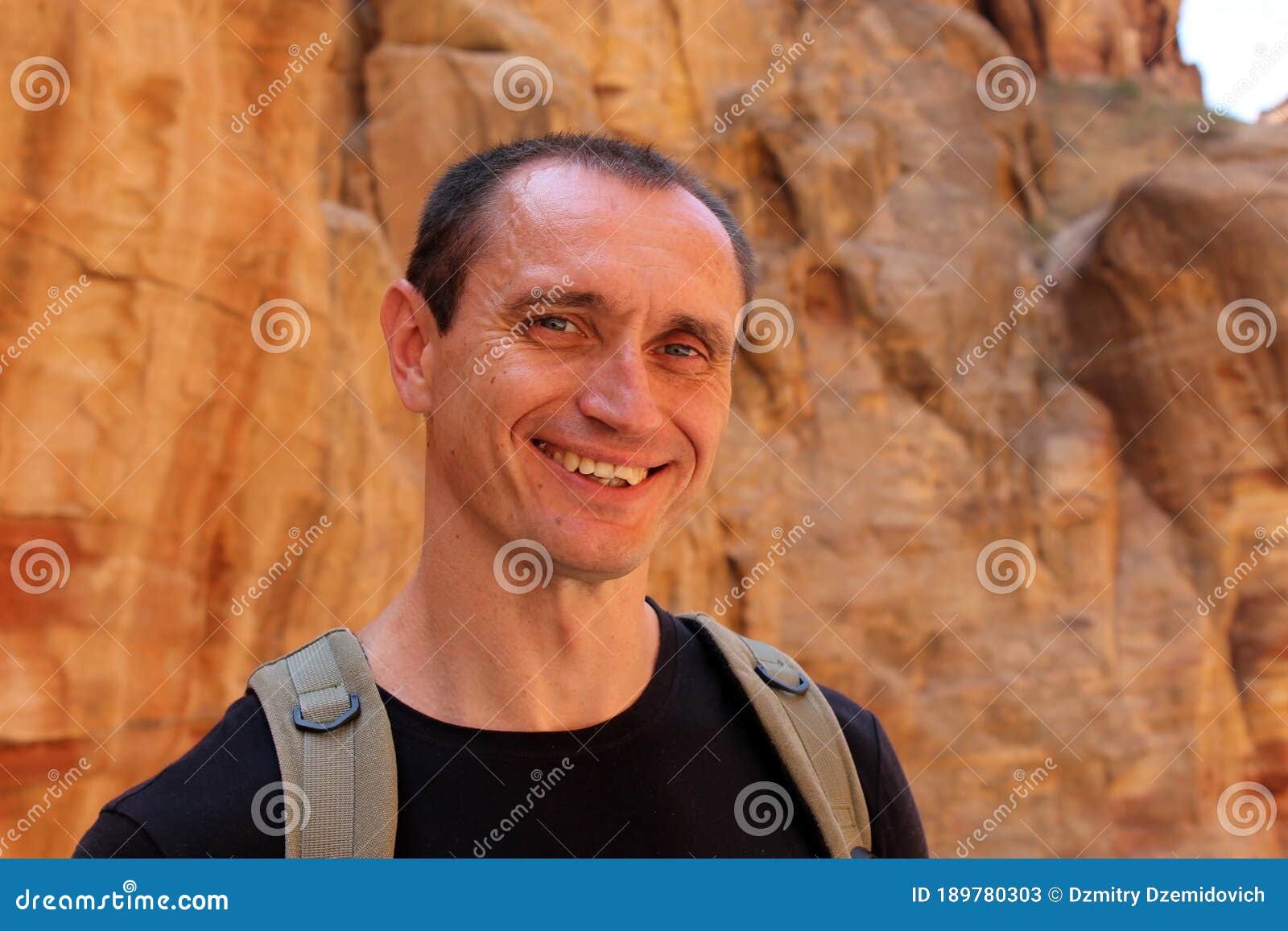 Sonriente Turista Europeo Con Ropa Negra Con Mochila En Petra En Jordania  Durante Un Viaje. Fondo Hermoso Imagen de archivo - Imagen de salud,  escalada: 189780303