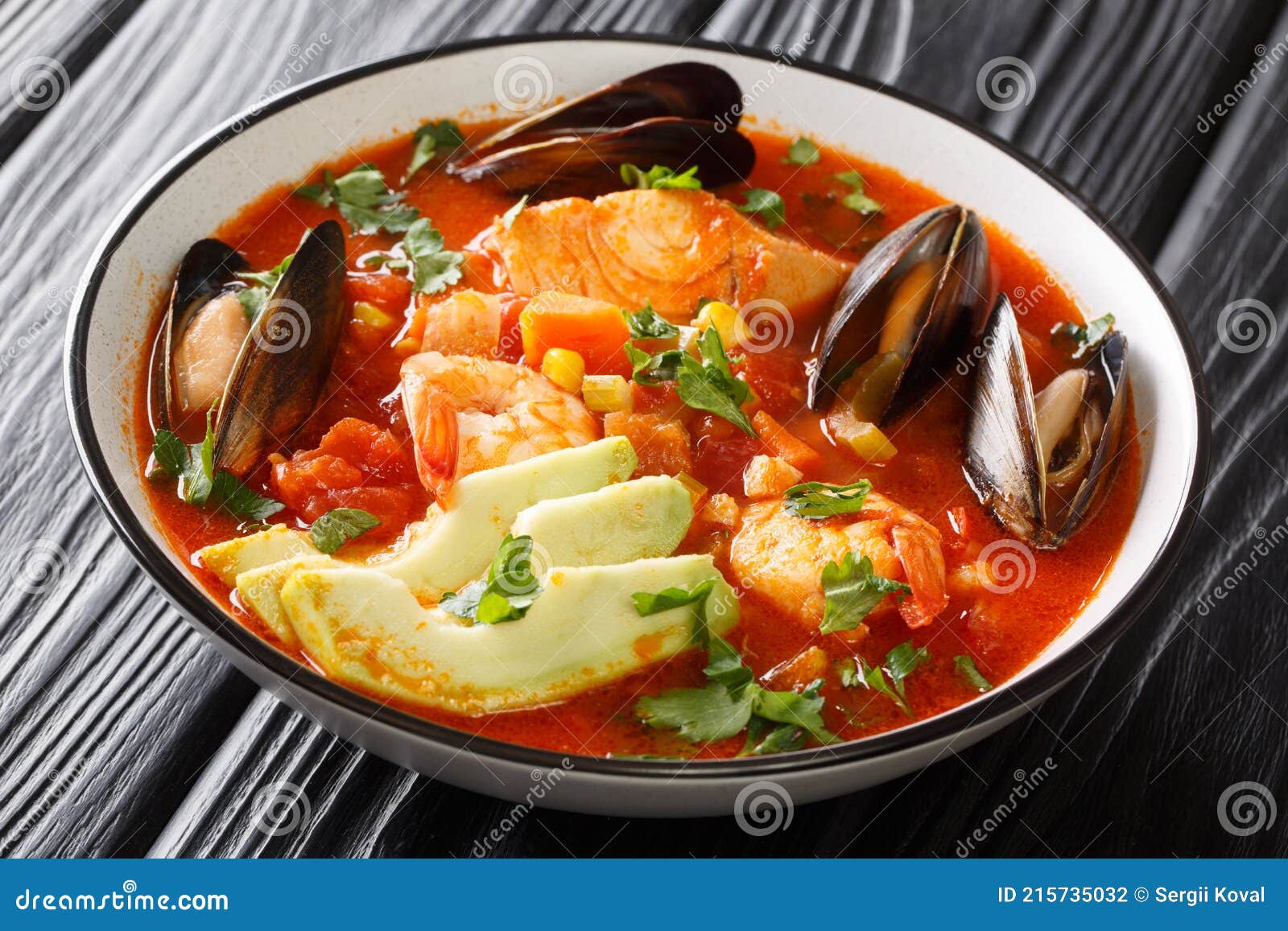 sopa de mariscos seafood soup with cod, shrimp, mussels, vegetables and avocado close-up in a bowl. horizontal