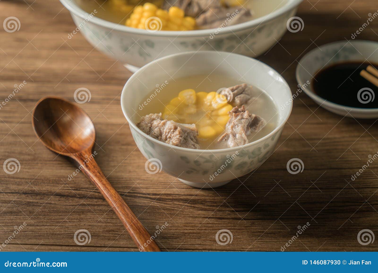 Sopa do osso do milho e da carne de porco, alimento chin?s delicioso As decorações da colher gourmet fresca horizontal branca da culinária do almoço do jantar da refeição da sopa de peixe do close up do fundo da bacia da mesa de jantar no milho amarelo saudável que cozinha especiarias douradas coloridas caseiros de madeira saborosos tradicionais da porcelana de Ásia dos reforços da proteína da costeleta da nutrição do nutriology da carne da dieta da caloria do cozinheiro chefe provam a luz do molho de soja