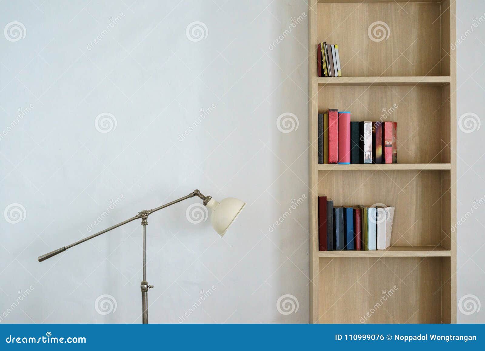 Una estantería con libros y una lámpara en la pared.