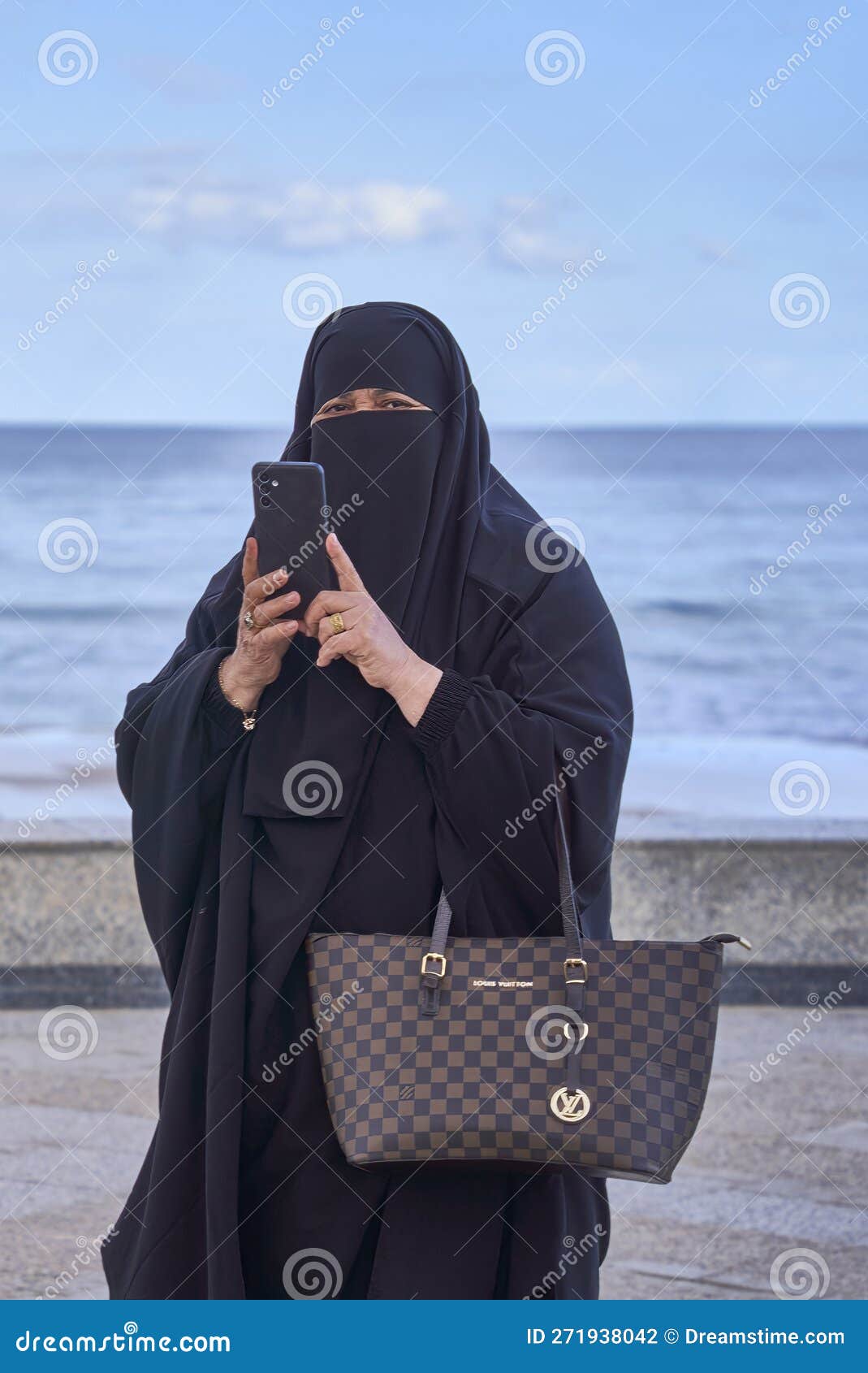 Elderly Muslim Arab Woman in Black Nikab and Abaya with a Handbag