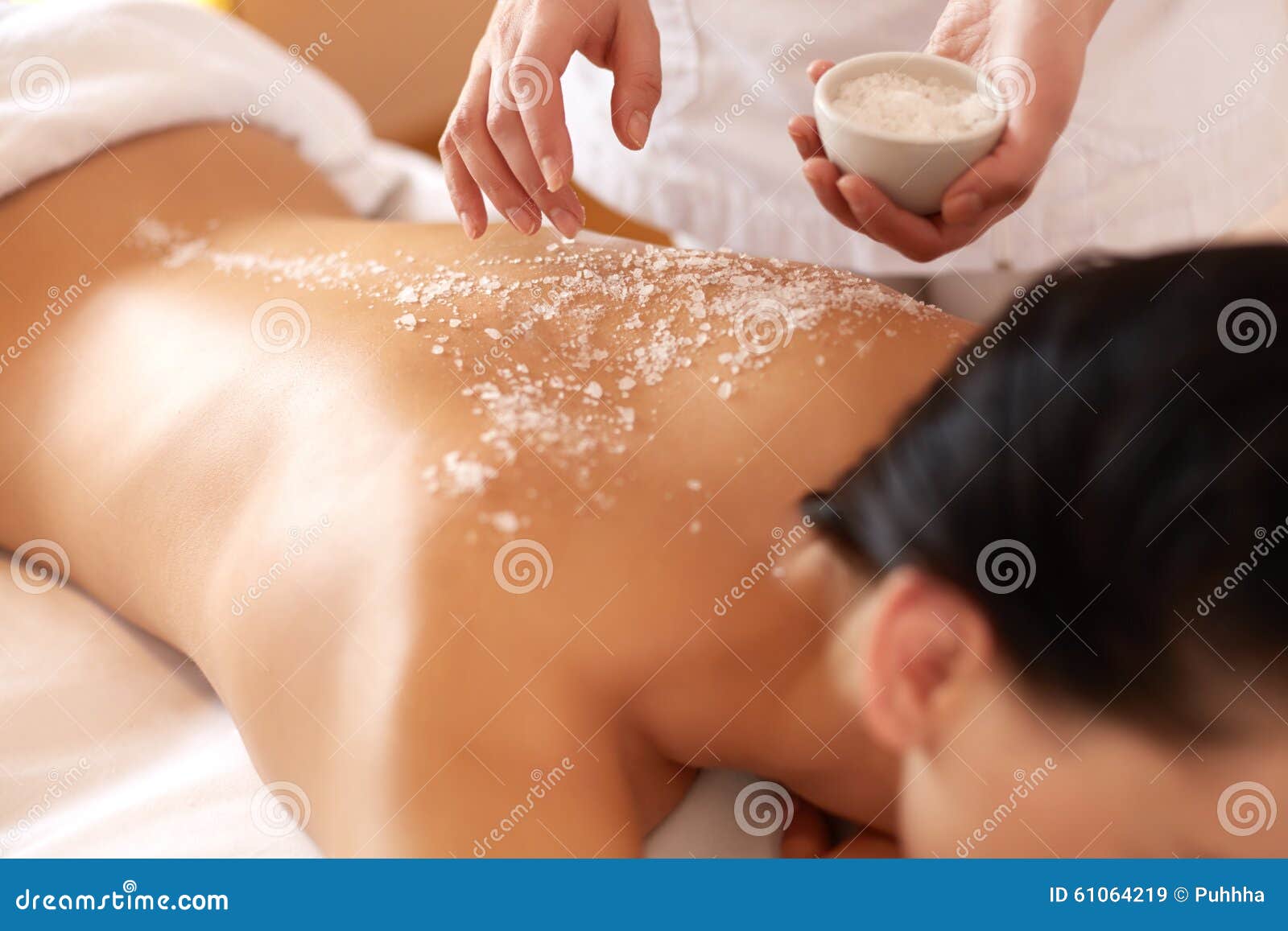 spa woman. brunette getting a salt scrub beauty treatment in the