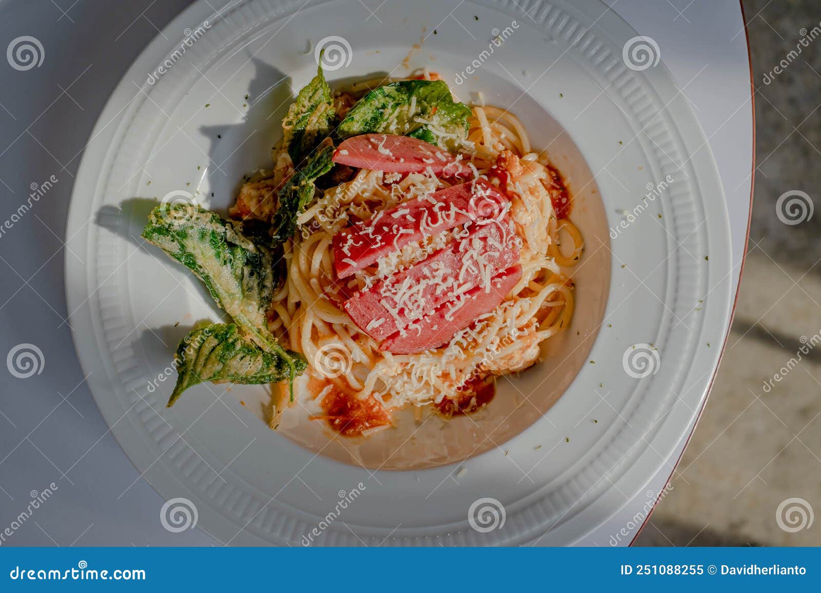 Spaghetti Bolognese with Spinach Chips on a White Plate and Table with