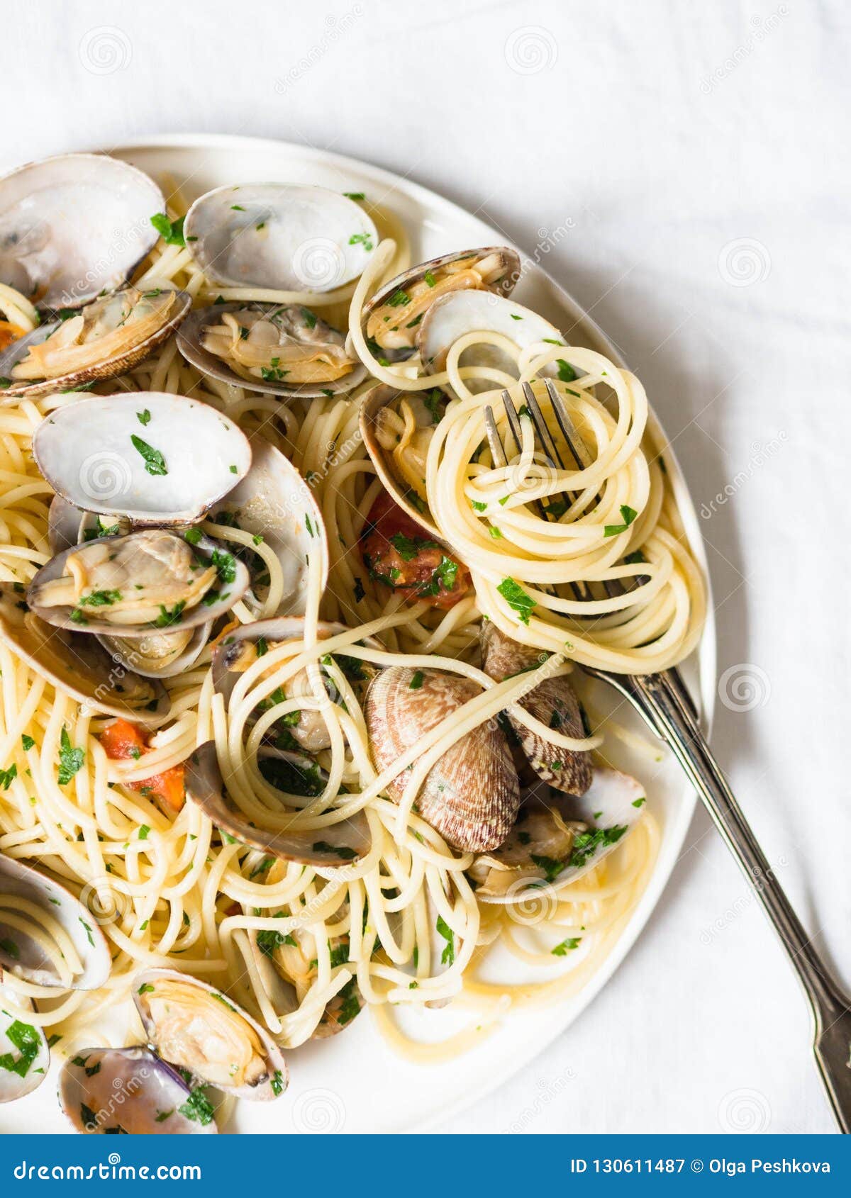 Spaghetti with Clams, Tomatoes, Garlic and Parsley on a White Plate and