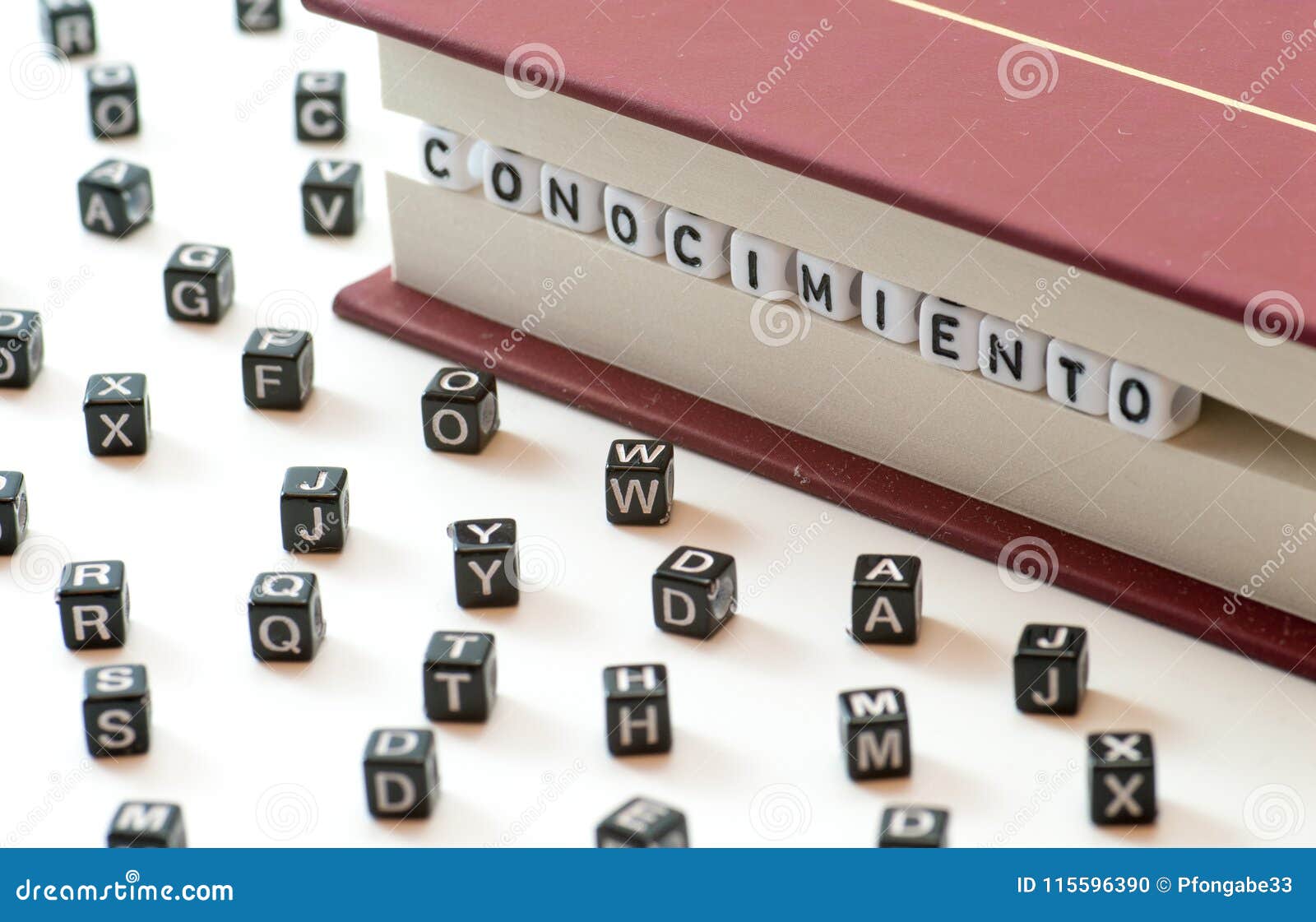 spanish word conocimiento meaning knowledge written with letters trapped between a book files and spread letters on white backgrou