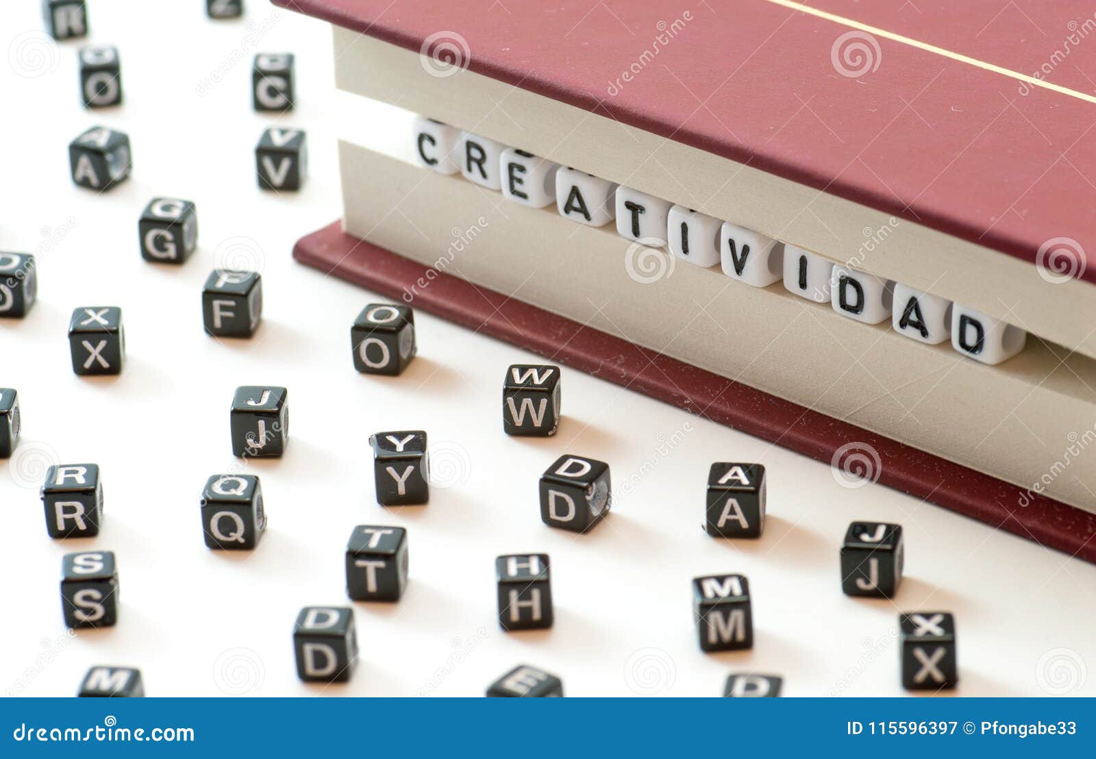 spanish word creatividad meaning creativity written with letters trapped between a book files and spread letters on white backgrou