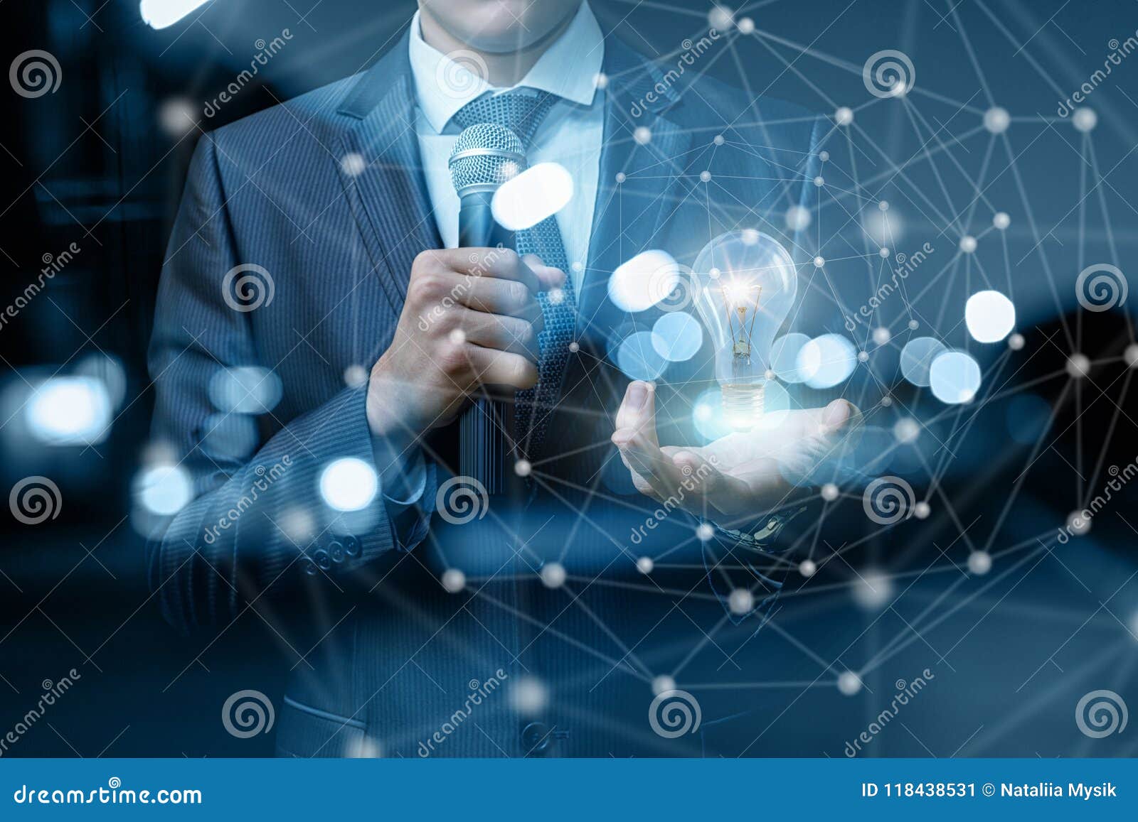 Speaker with Microphone in Hand Shows a Burning Bulb. Stock Image