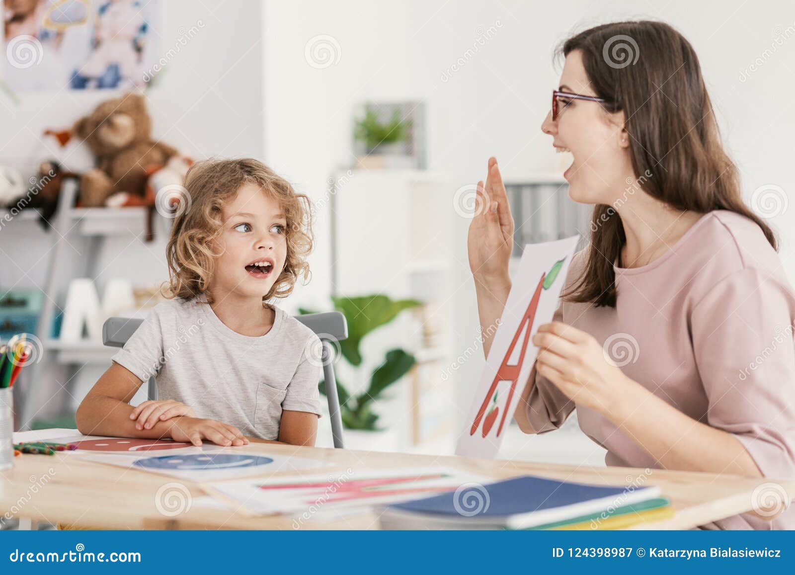 speech therapist teaching letter pronunciation to a young boy in