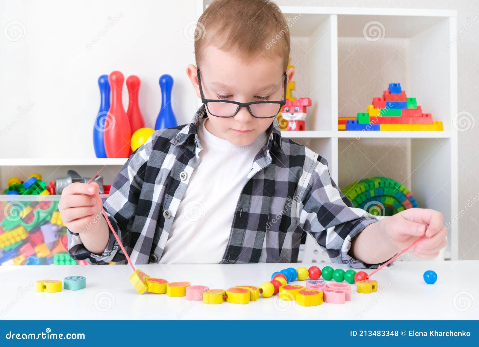 Speech Therapy, the Development of Fine Motor Skills. Toddler Boy is Stringing Beads on a String