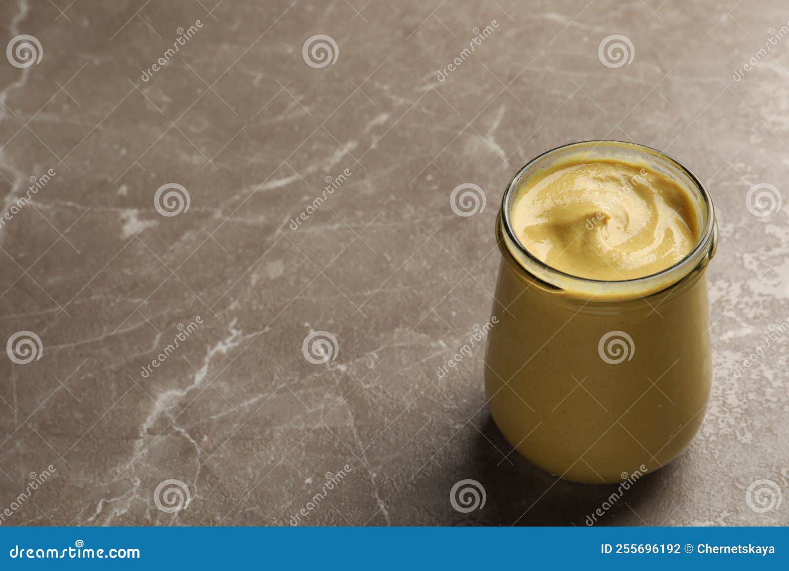 Spicy Mustard in Glass Jar on Brown Marble Table. Space for Text Stock