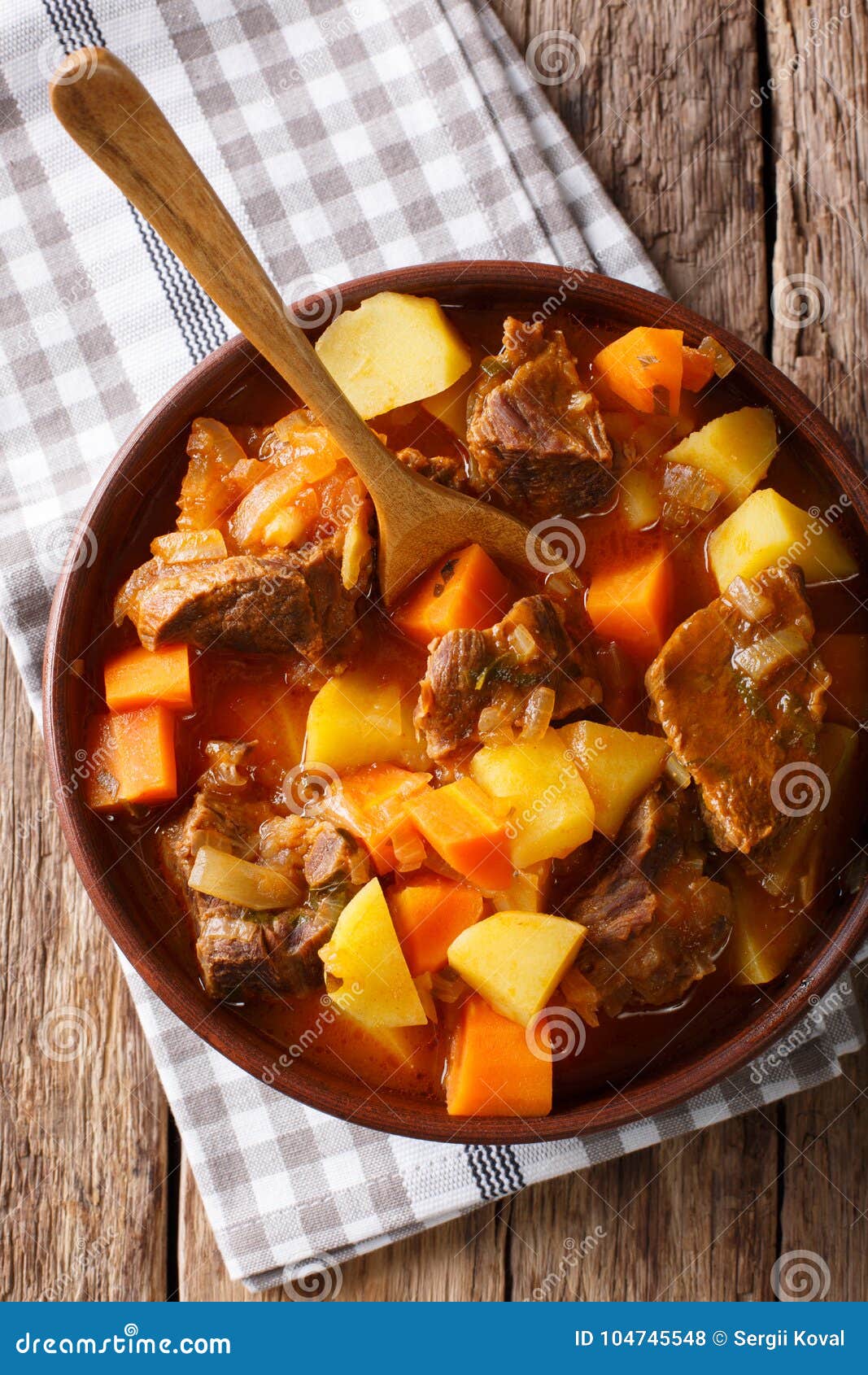 spicy stew estofado with beef and vegetables in a bowl close-up. vertical top view