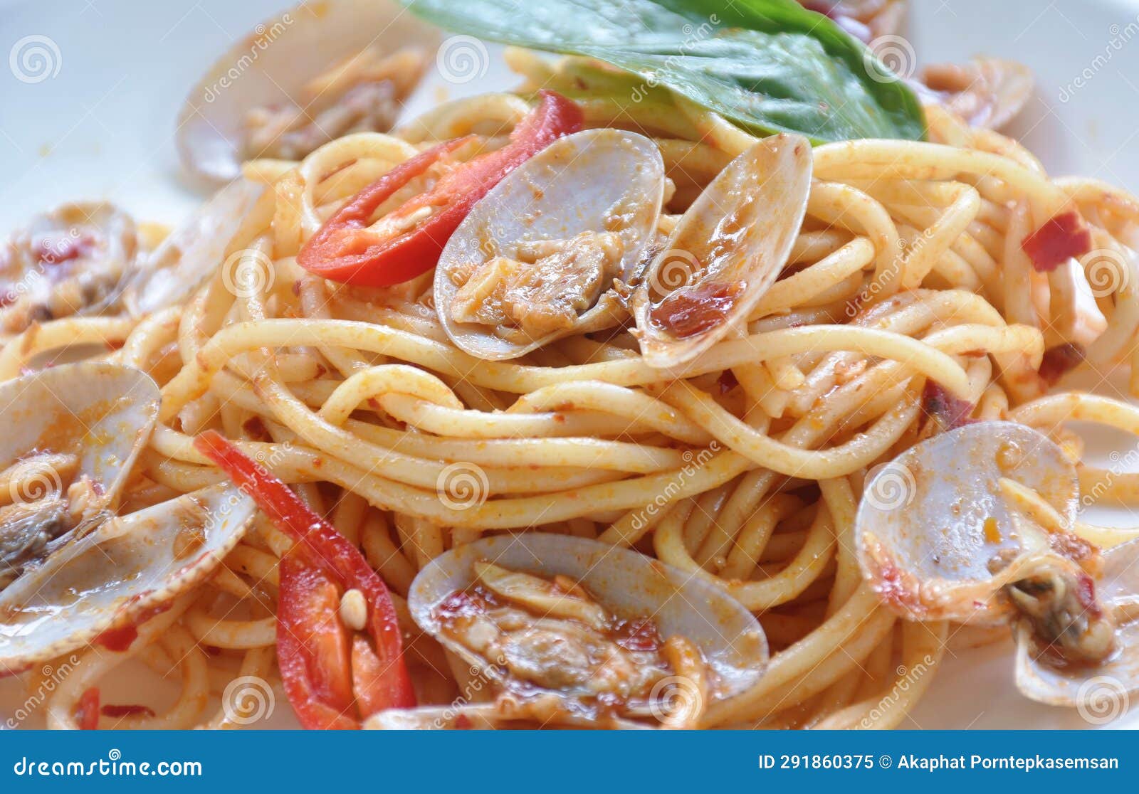 Spicy Stir Fried Spaghetti Clams with Pepper and Basil Leaf on Plate