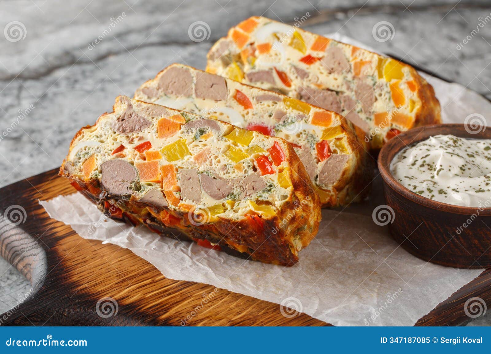 spicy terrine pie with chicken liver, carrots, peppers, herbs and eggs close-up on a wooden board. horizontal