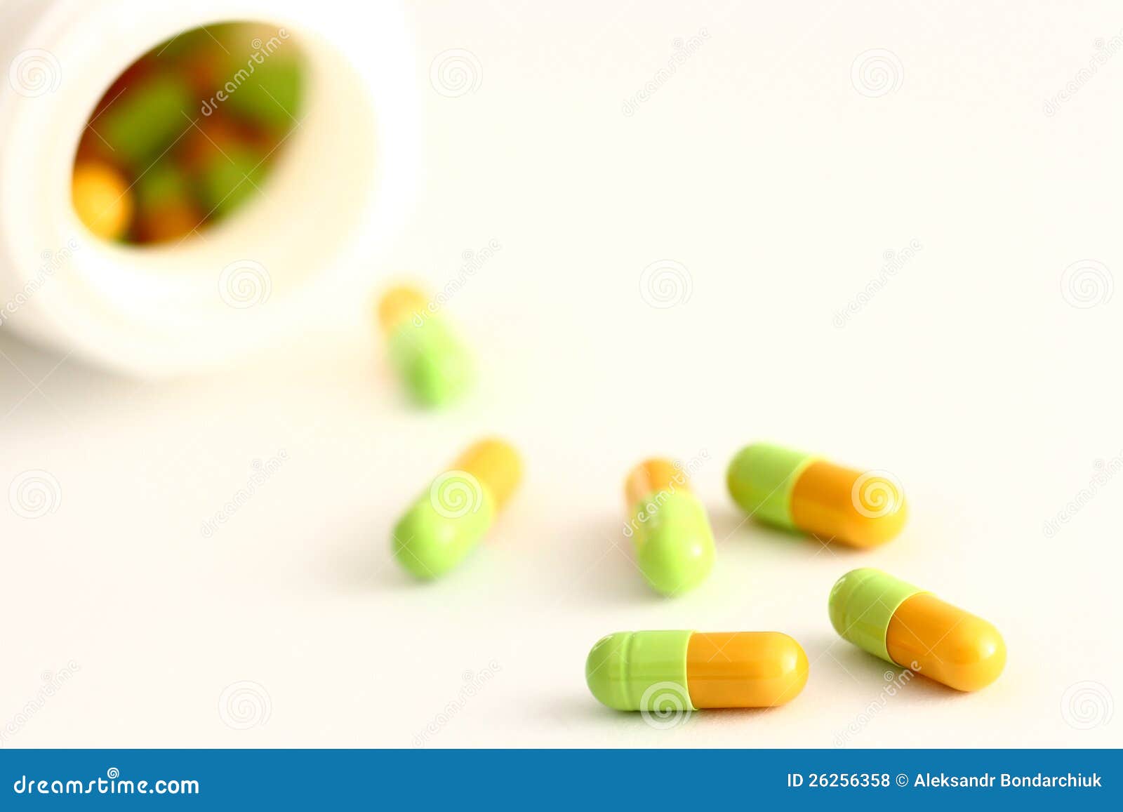 Spilled capsules from prescription bottle. Colorful pills lying on the table