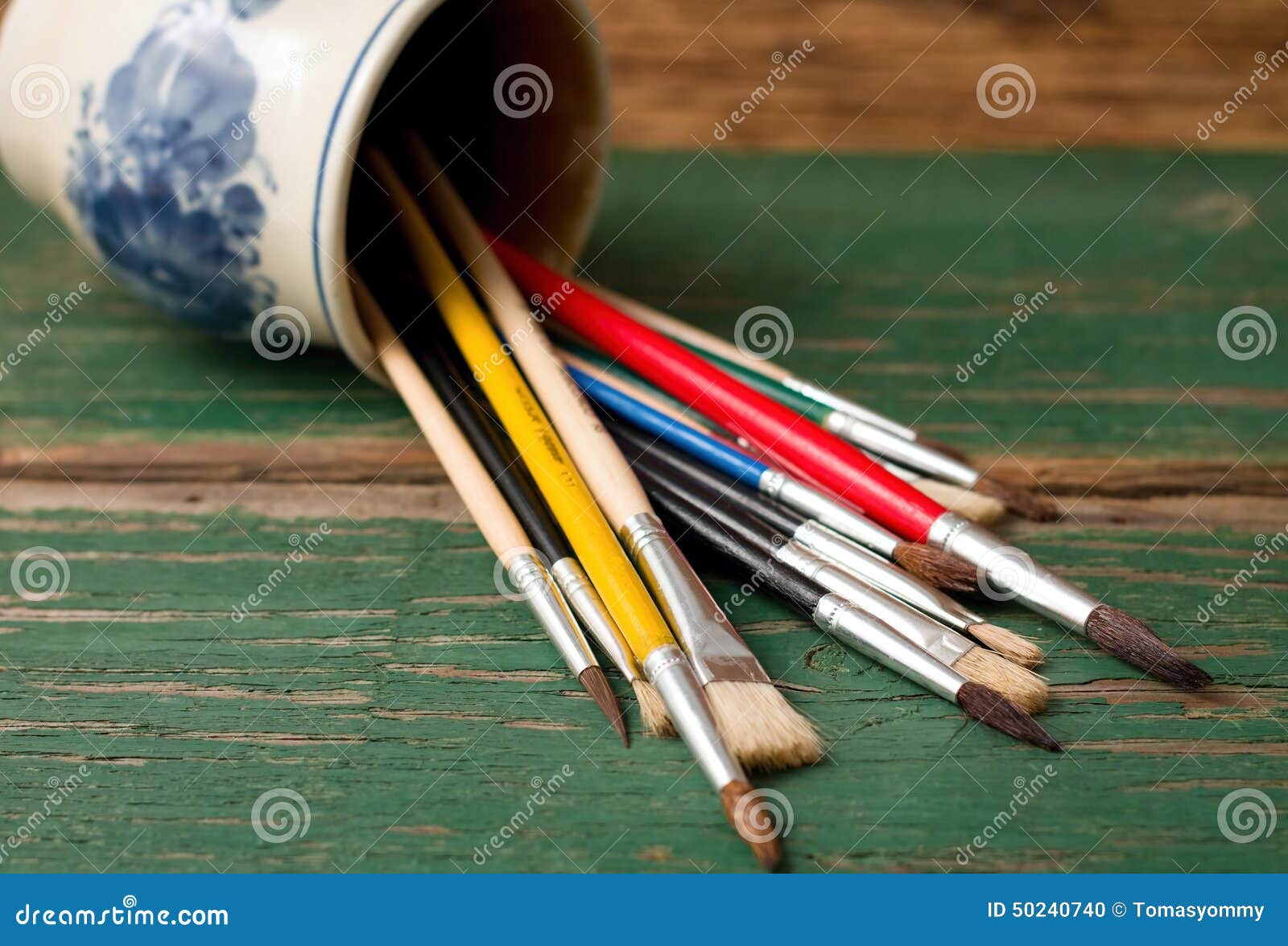 Spilled Ceramic Cup with Paintbrushes on Green Board Stock Photo