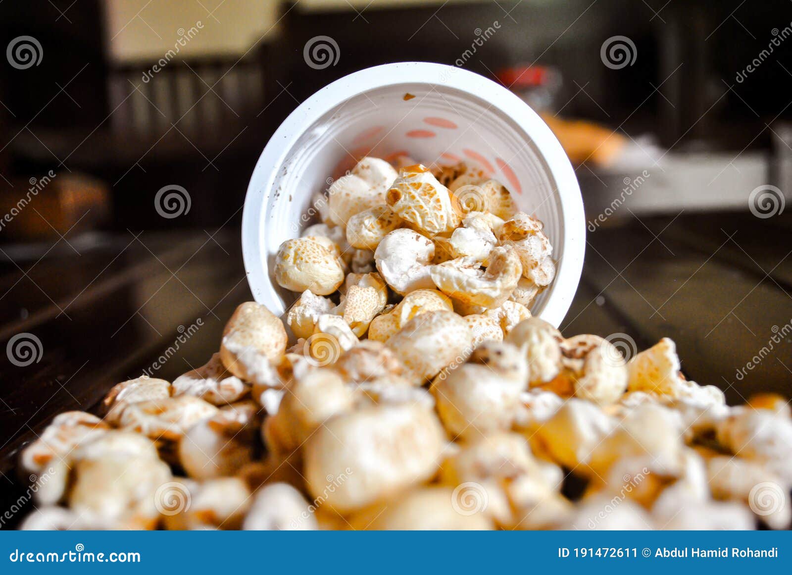 Spilled Popcorn from the Red Spot Bucket on Wooden Table Stock Image