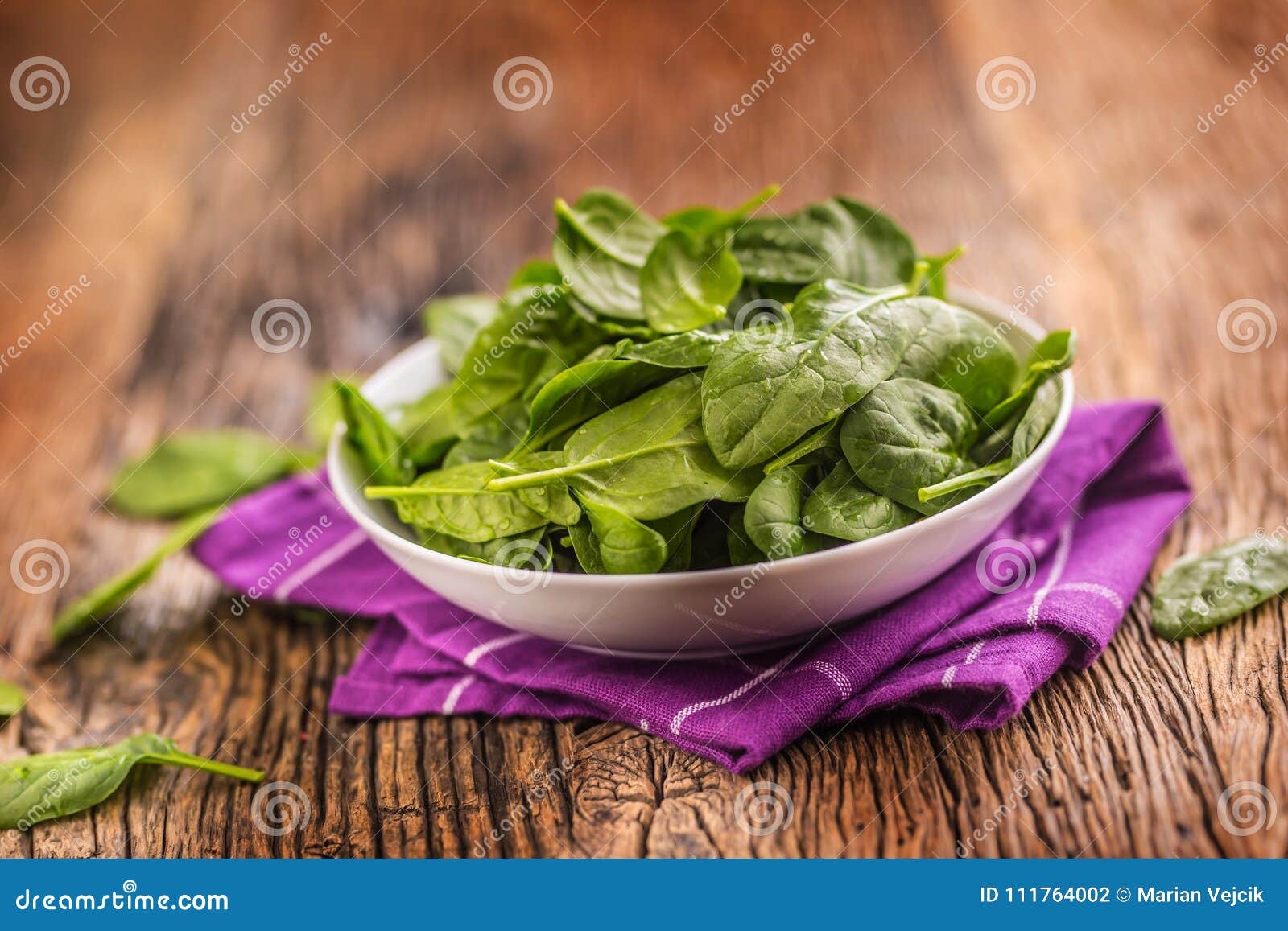 Spinach. Fresh Baby Spinach Leaves in Plate on Woden Table Stock Photo
