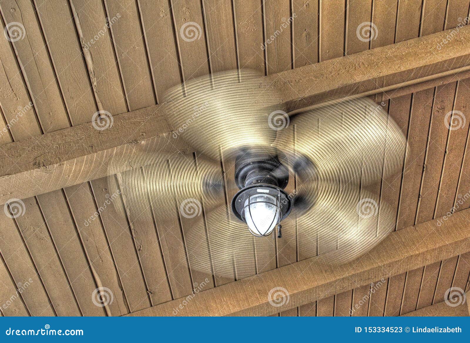 Spinning Ceiling Fan With Light On Rustic Wood Ceiling Stock