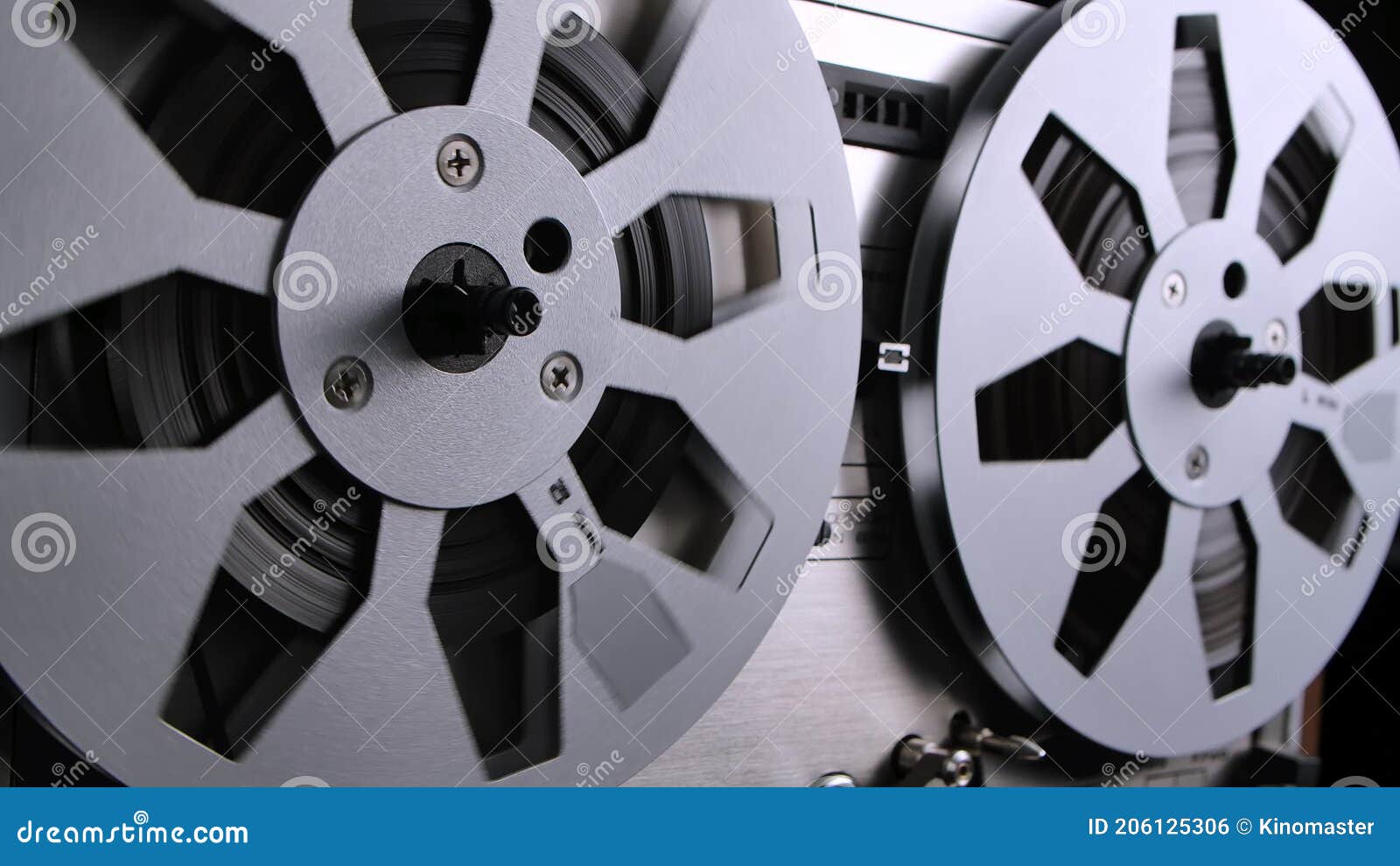 Spinning takeup reel of old analog reel-to reel audio tape recorder. Form  of magnetic tape audio recorder in which the recording medium is held on a  reel that is not in a