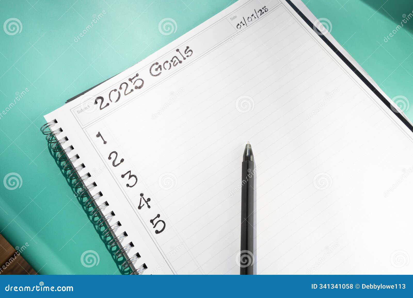 spiral bound notebook open to a page with handwritten text 2025 goals and numbered one through five with a pen on a bluish-green
