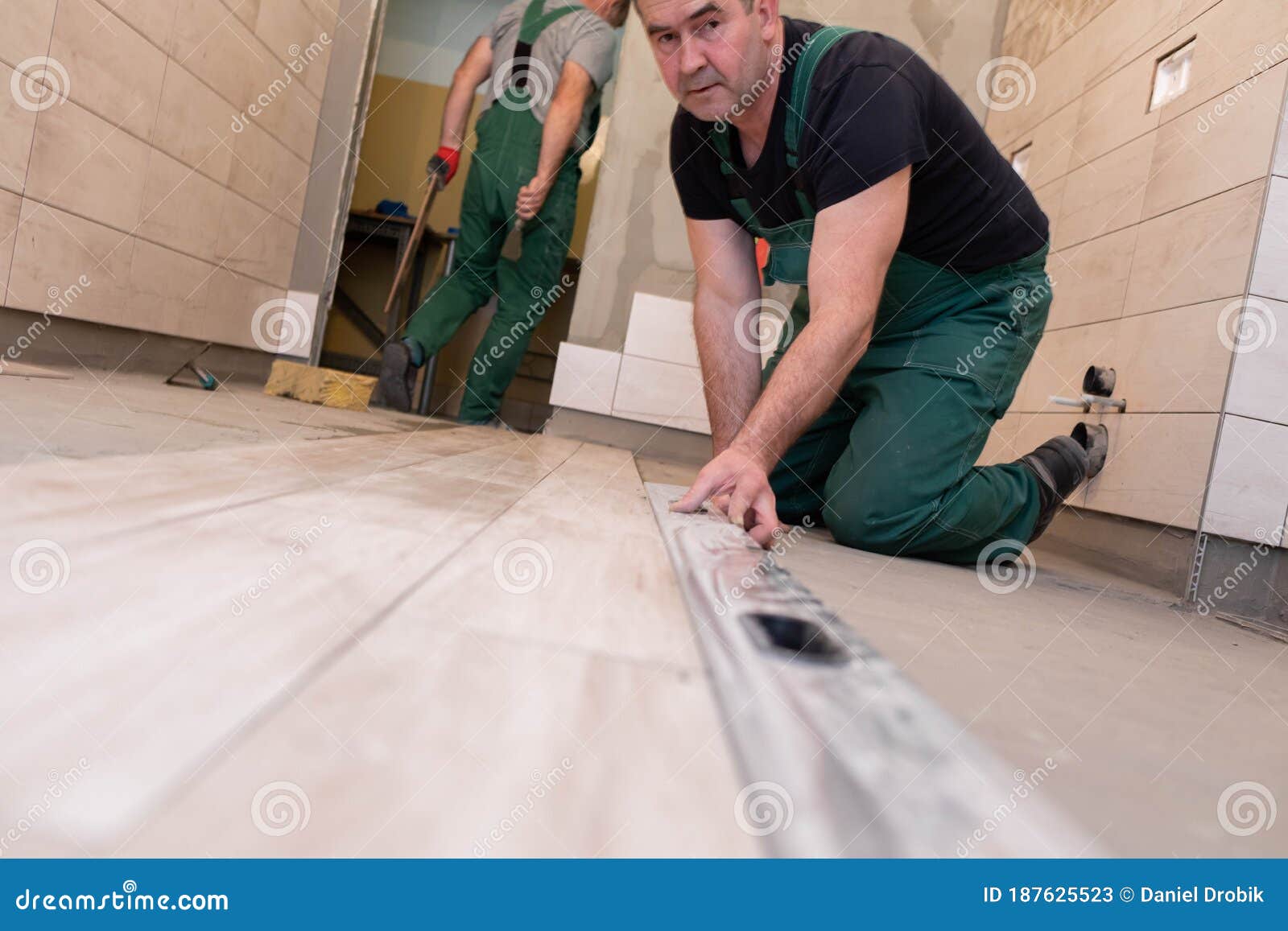Free Photo  Builder checks the quality of the laid tiles with a manual  bubble level construction worker installing ceramic floor tiles on  construction sites floor repair selective focus