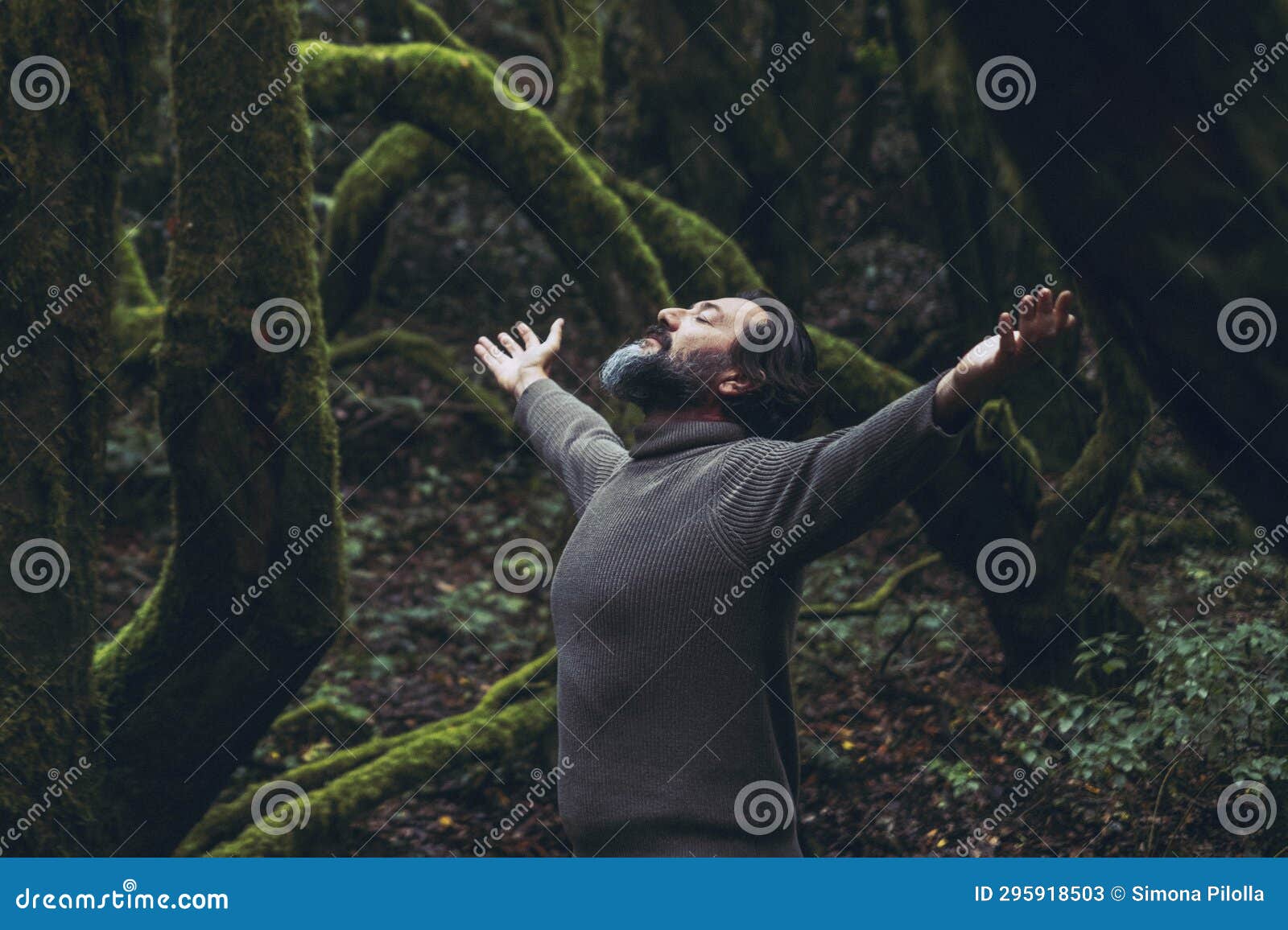 spiritual zenlike nature love people. one man with closed eyes and outstretching arms in the nature forest green trees scenic